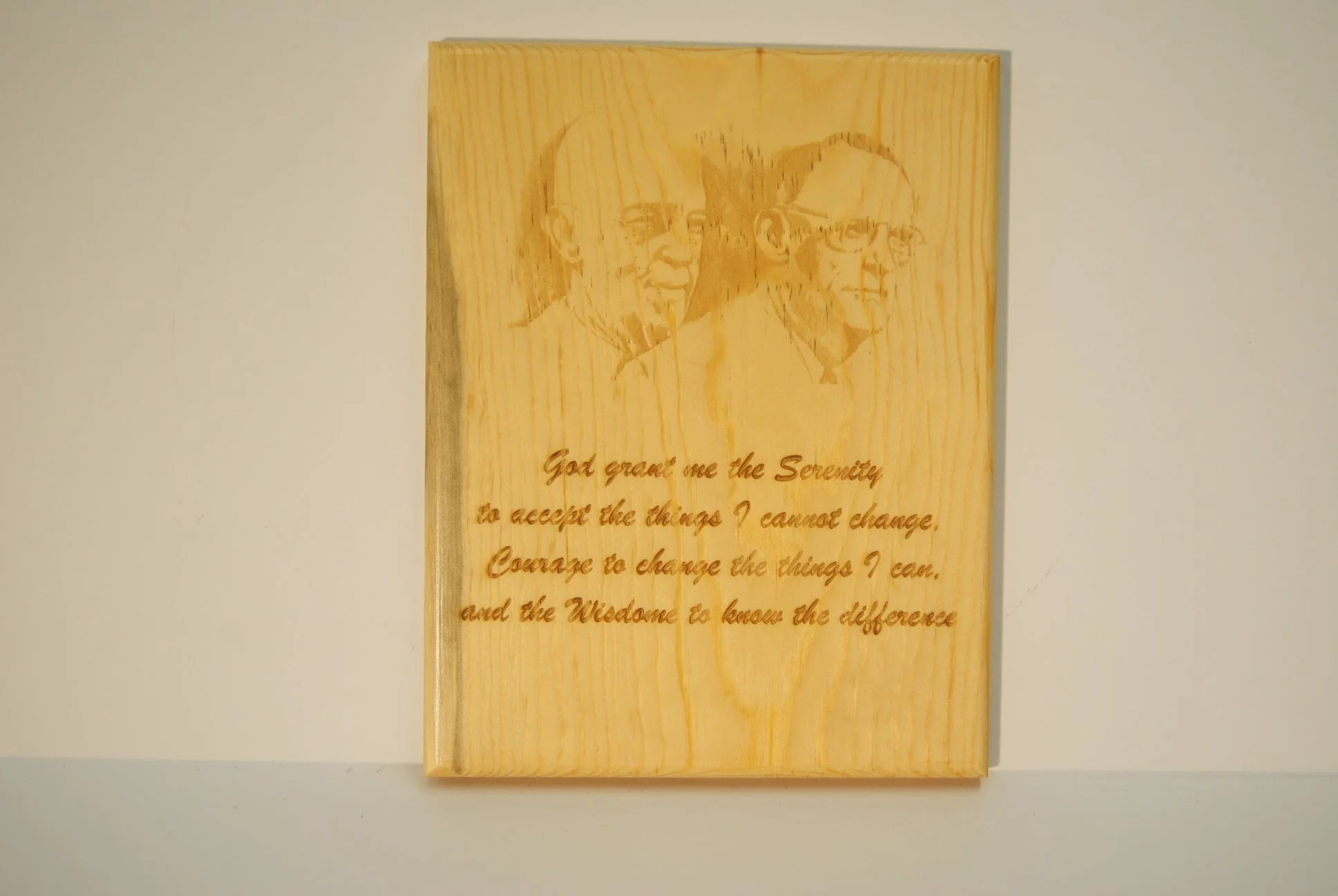 Wooden plaque or artwork with engraved portrait images of two men, one older with glasses, and a quote about serenity, courage, and wisdom.