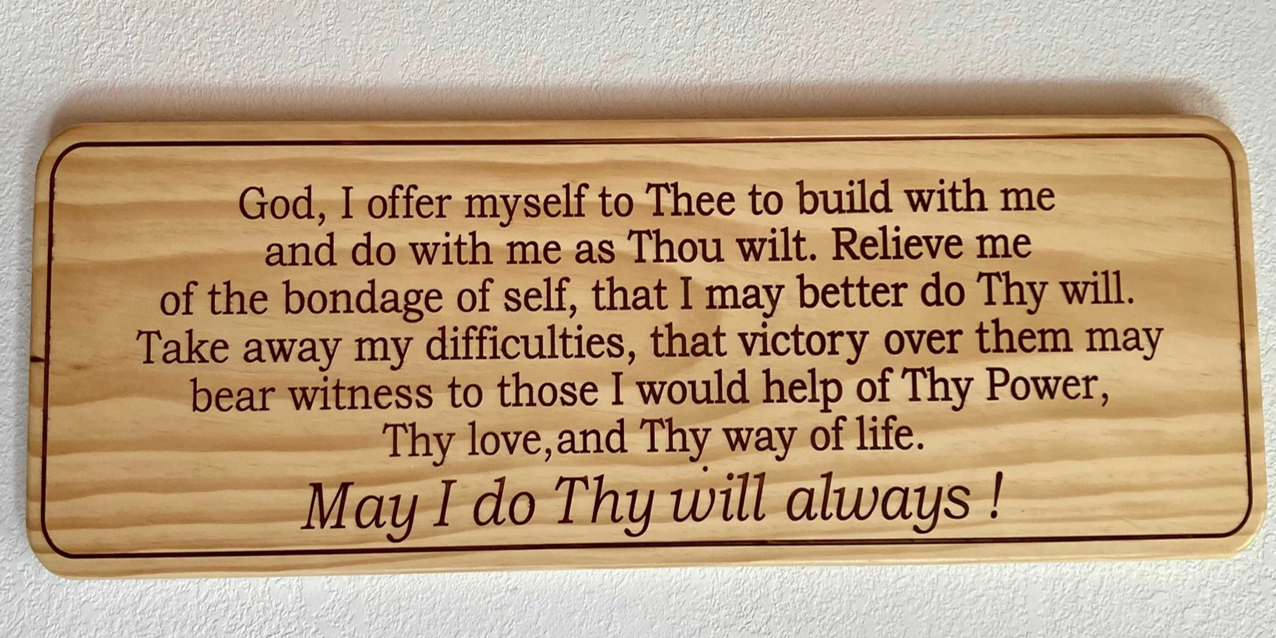 A wooden plaque with a religious prayer written in dark brown text.