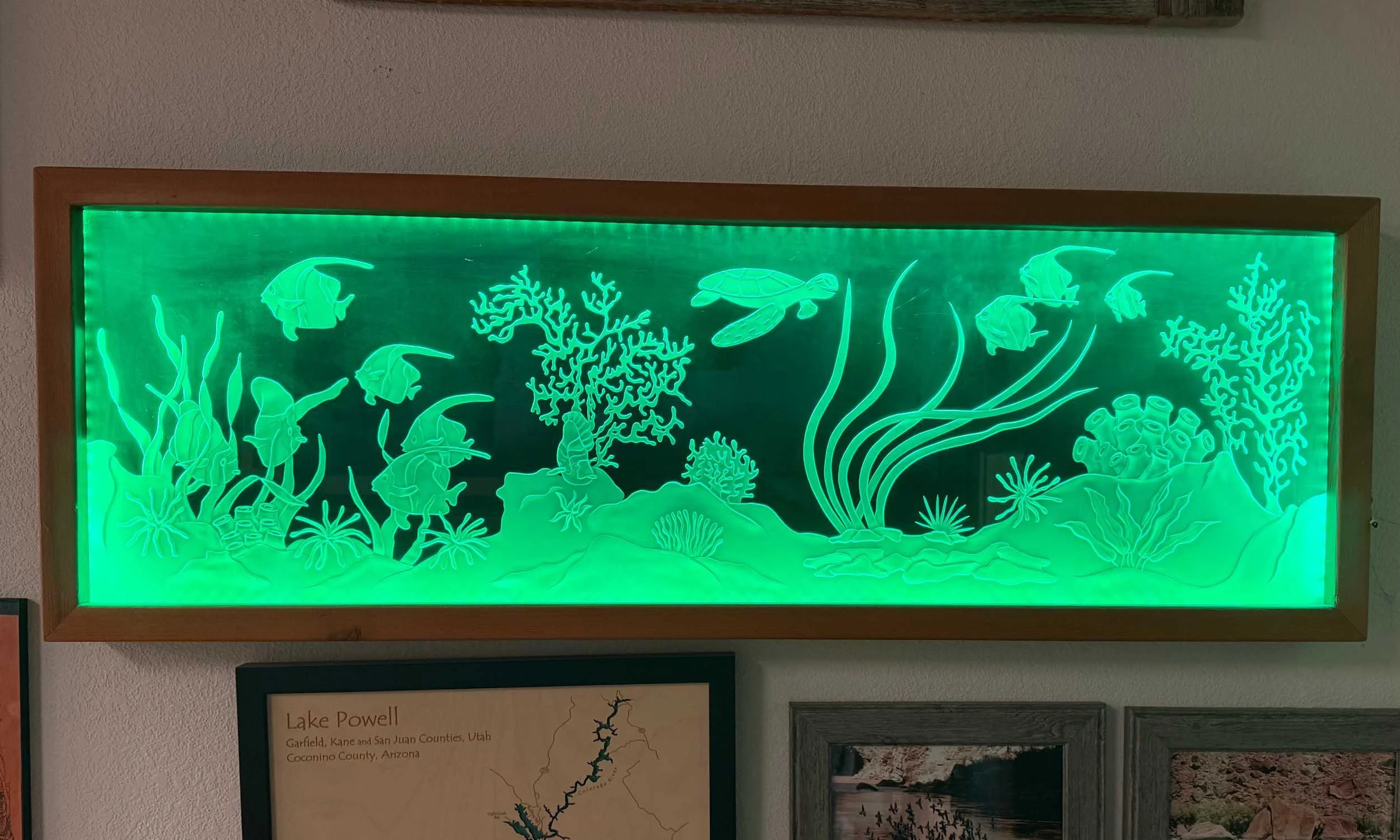 Glow-in-the-dark framed artwork of an underwater scene with fish, coral, seaweed, and sea creatures.