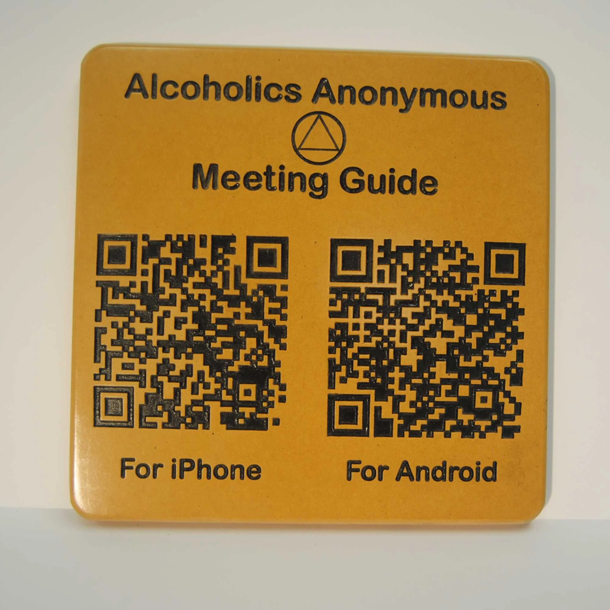 Yellow card with black text and QR code, labeled 'Alcoholics Anonymous Meeting Guide' and includes icons for iPhone and Android versions.