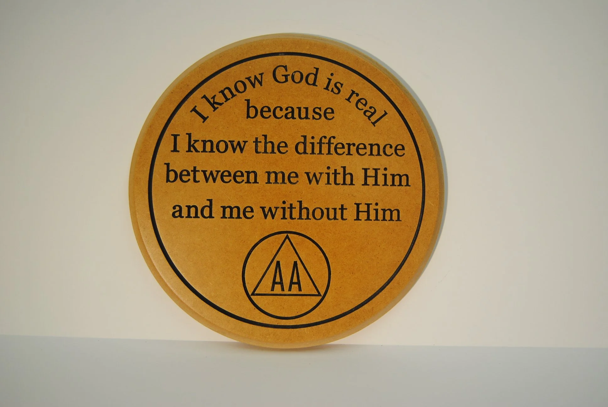 Round orange plaque with black text that reads, "I know God is real because I know the difference between me with Him and me without Him" and has a small AA (Alcoholics Anonymous) logo at the bottom.