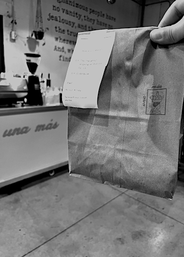 Una Más branded bag with order receipt at the coffee cart pop-up
