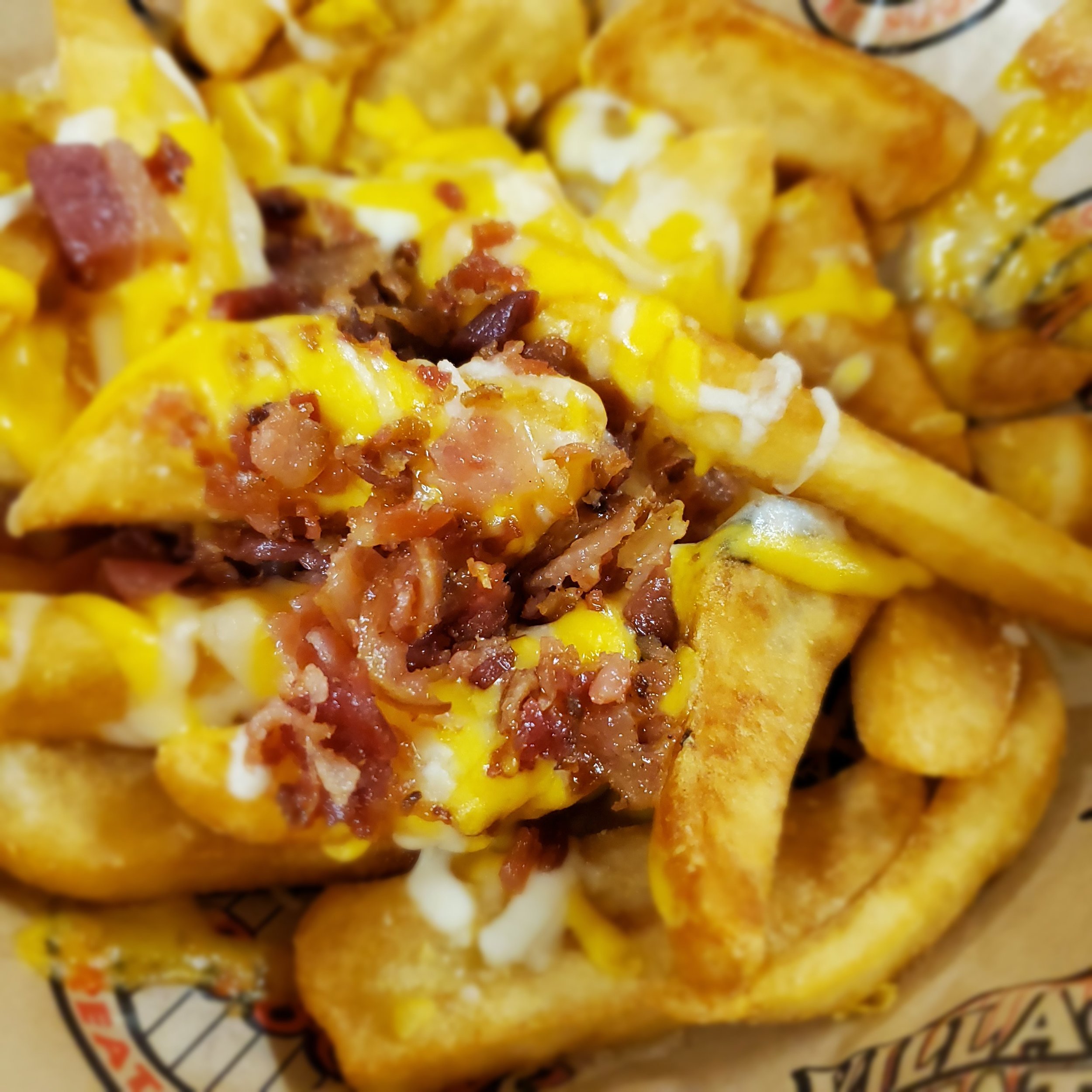 Close-up of Nachos with melted cheese, diced tomatoes, ground meat, and jalapenos on a plate.