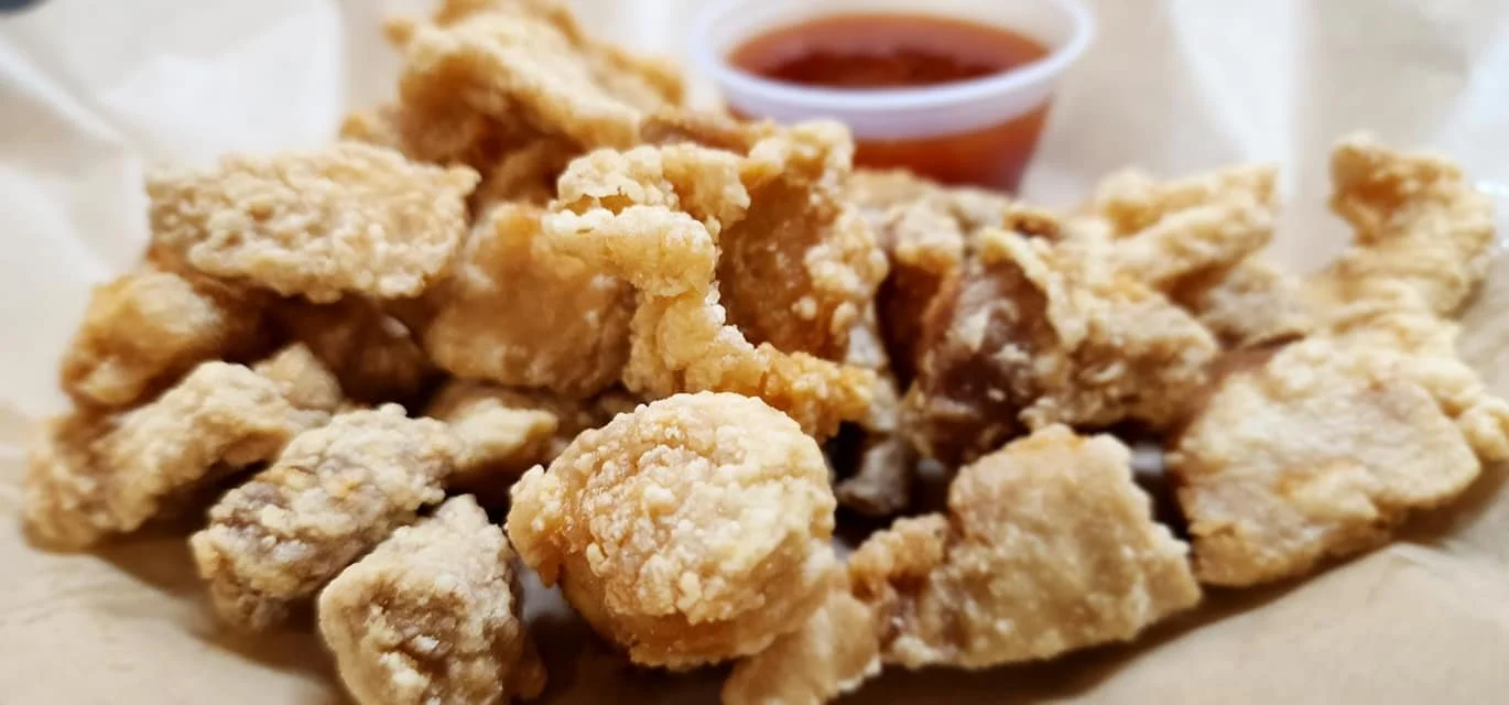 Close-up of fried chicken pieces with a small cup of dipping sauce in the background.