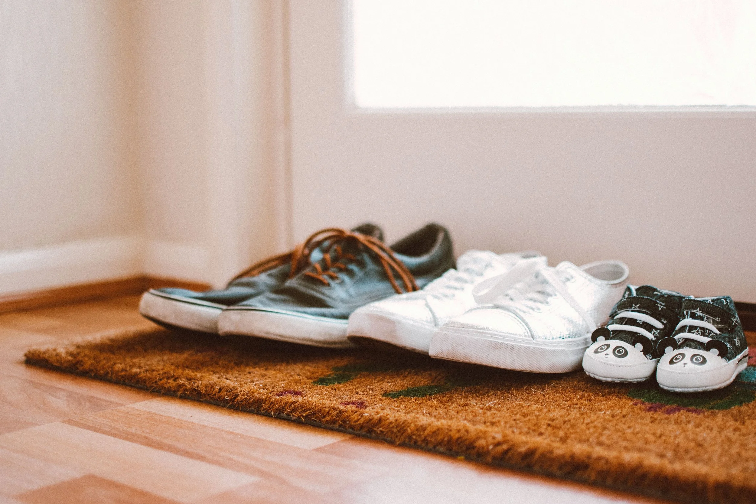 Family shoes lined up on a welcome mat, in their rented home