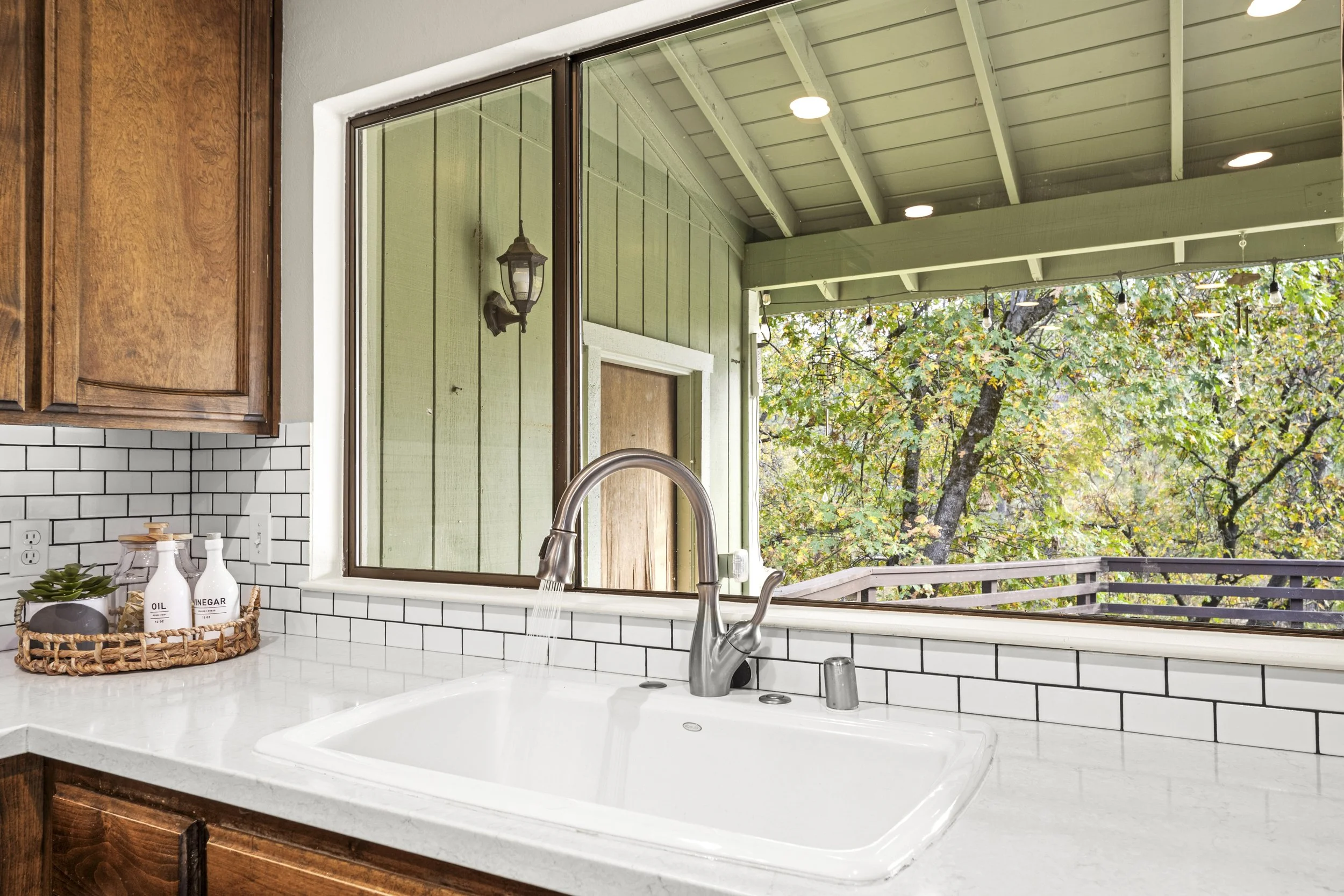 Kitchen sink with a view of a porch and trees outside through a large window