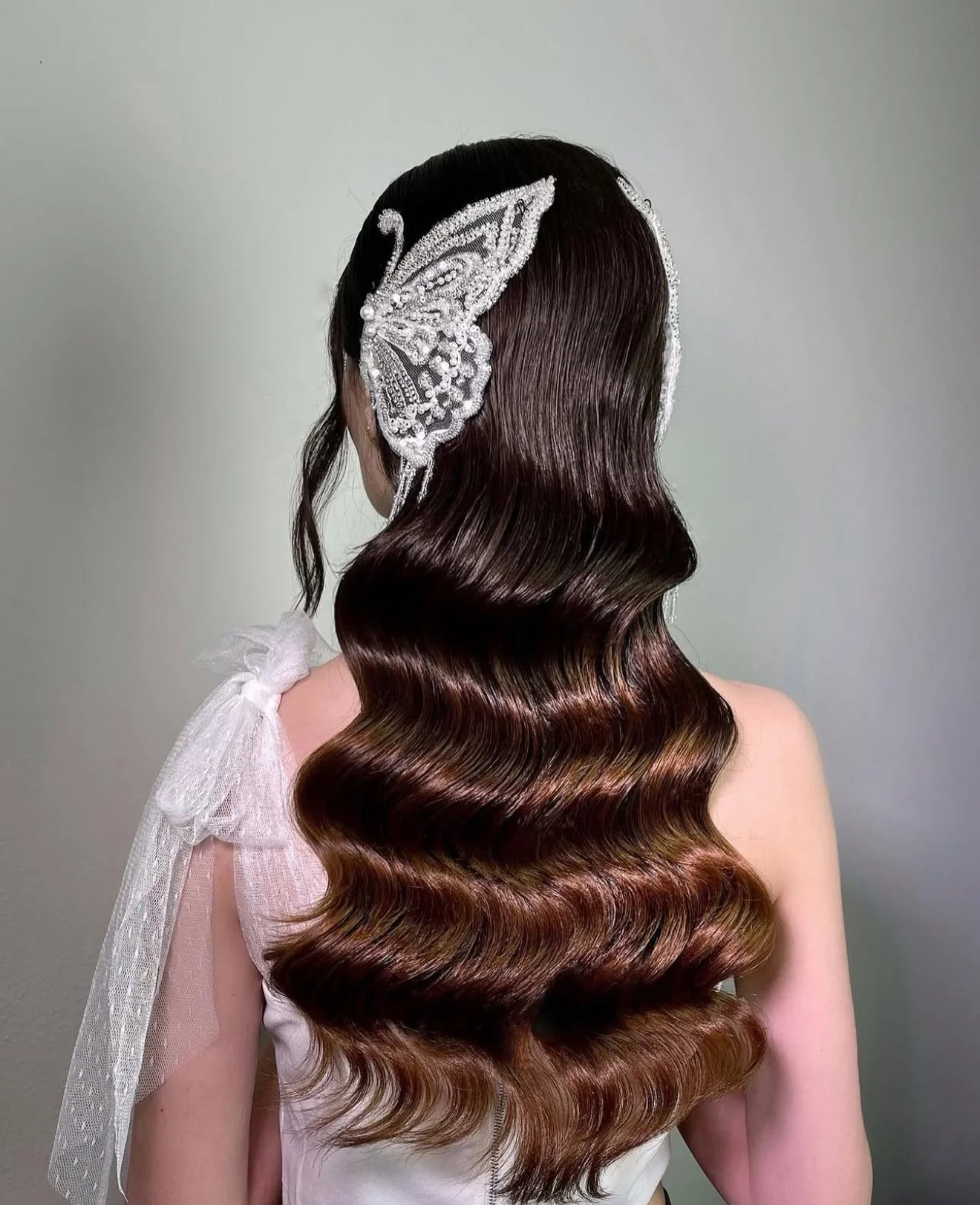 Elegant bridal waves with butterfly hair accessory — bridal hair styling by ESQAO Academy Los Angeles