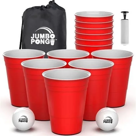 Set of red plastic cups, two white foam balls with Jumbo Pong logo, a black carry bag with Jumbo Pong branding, a ping pong paddle, and a pump for inflatable balls.