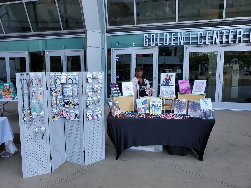 Local artisan vendor displaying handmade jewelry, earrings, accessories, and art prints