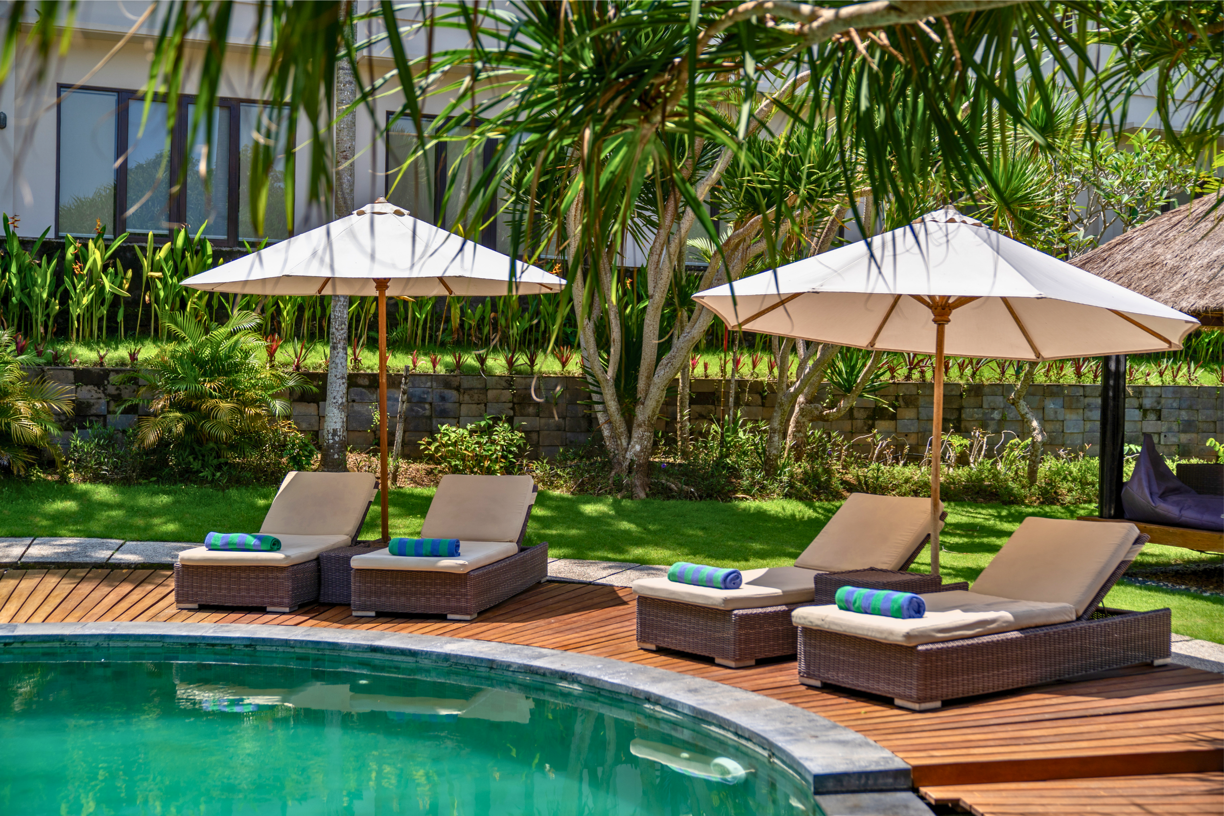 Tranquil resort pool with sun loungers at Bali yoga and pilates retreat Indonesia tropical garden surrounded by lush palm trees
