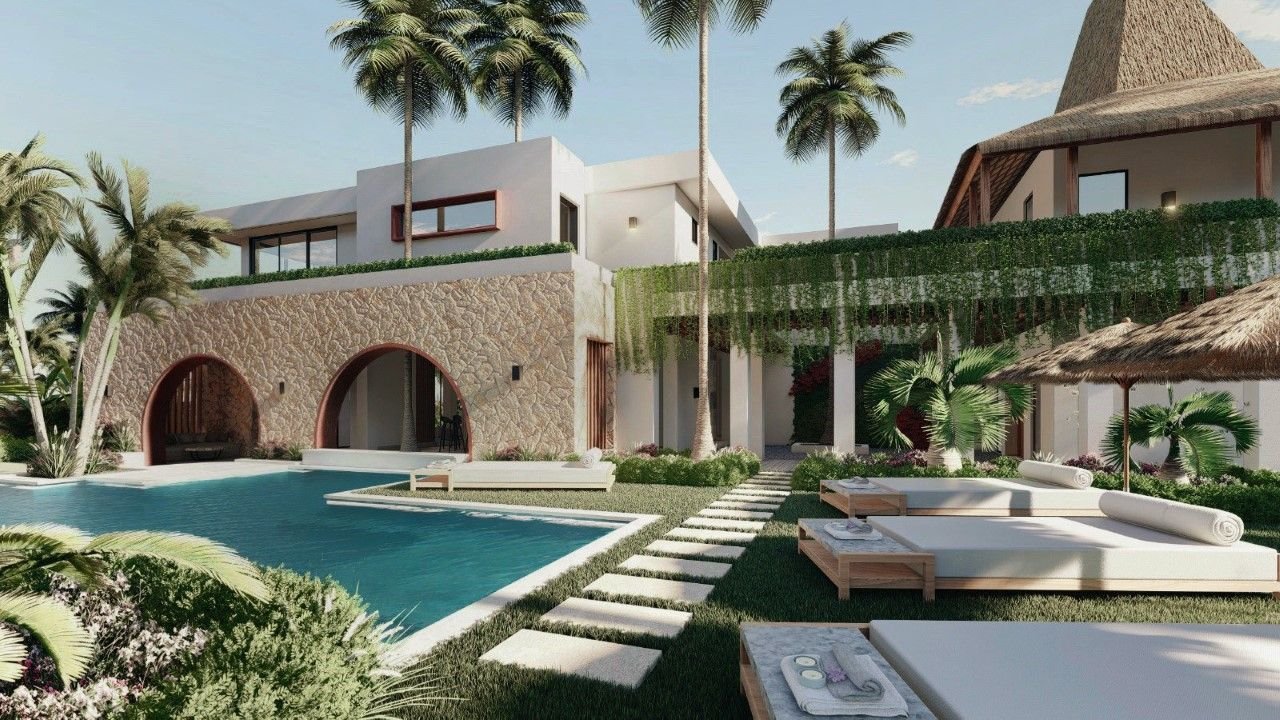 Luxury resort with a swimming pool, sun loungers with towels, palm trees, and modern white buildings with stone and thatched roof accents.