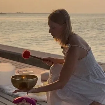 Sunset sound healing singing bowl meditation on dock at Sumba yoga and pilates retreat Indonesia evening wellness ritual by the water