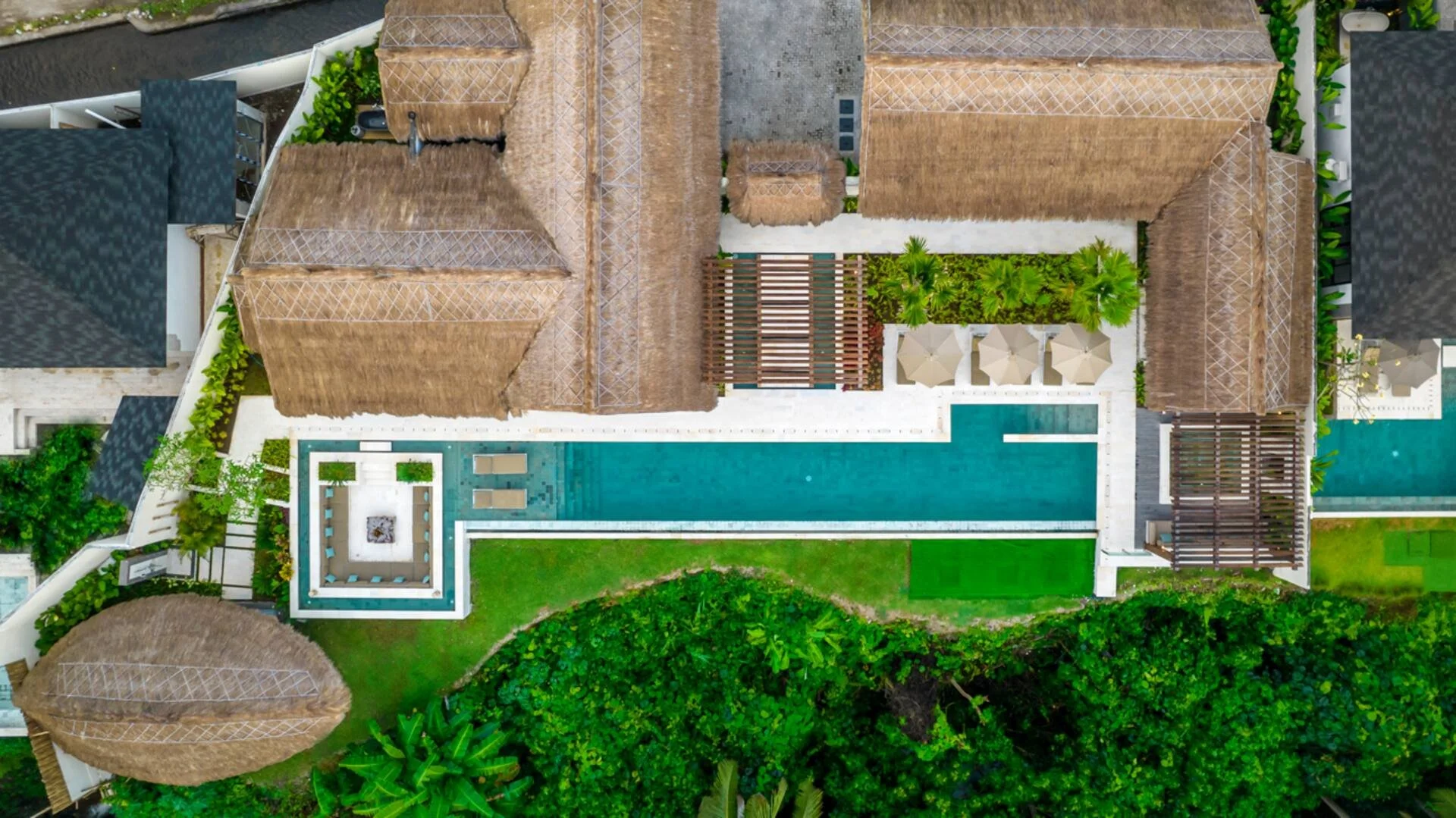 Aerial view of luxury yoga and pilates resort Bali Indonesia with thatched bungalows swimming pool and tropical garden from above