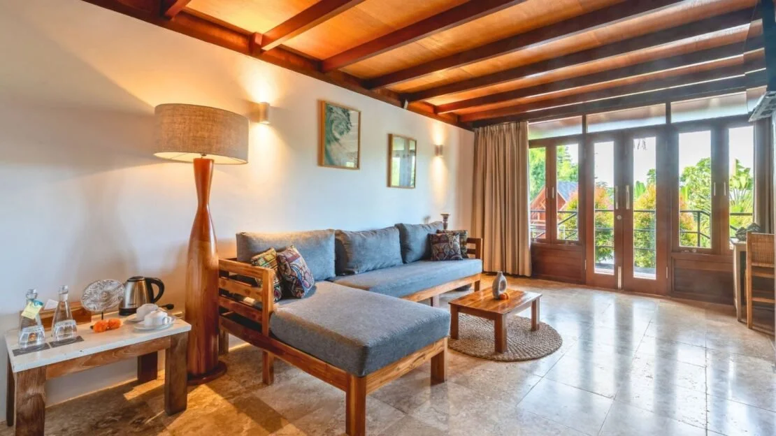 Spacious villa living room at Bali yoga and pilates retreat Indonesia with natural wood ceilings and large windows overlooking tropical garden