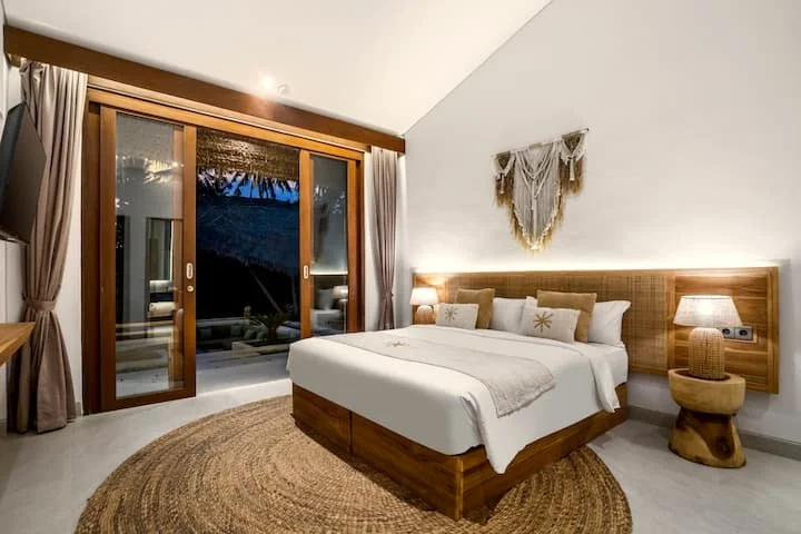 Luxury bedroom villa accommodation at Bali yoga and pilates retreat Indonesia with glass doors opening to tropical garden view