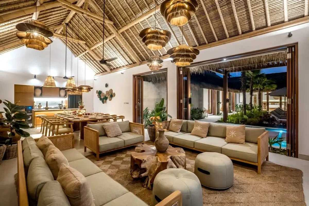 Open-plan luxury villa living room at Bali yoga and pilates retreat Indonesia with pool and thatched roof tropical indoor outdoor design