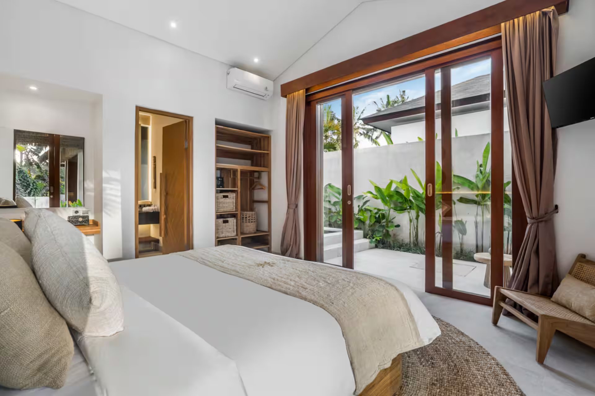 Elegant villa bedroom at Bali yoga and pilates retreat Indonesia with garden view sliding doors and luxury natural wood finishes