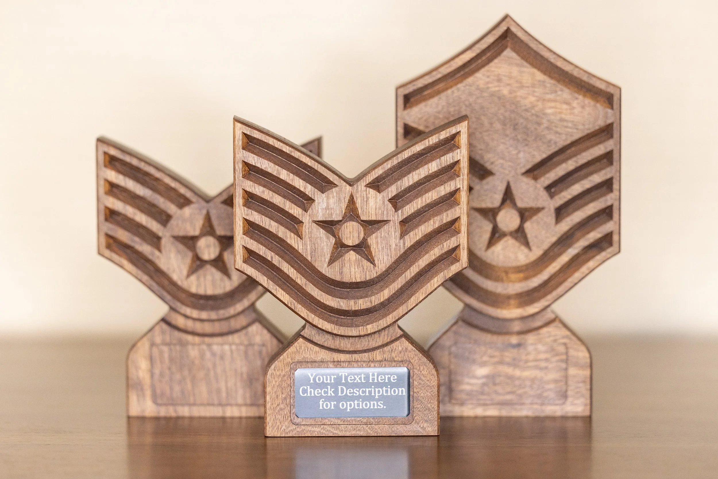 Three wooden star-shaped award trophies with engraved star patterns, arranged on a wooden surface, with a small grey label on the front of the middle trophy that reads 'Your Text Here Check Description for options.'