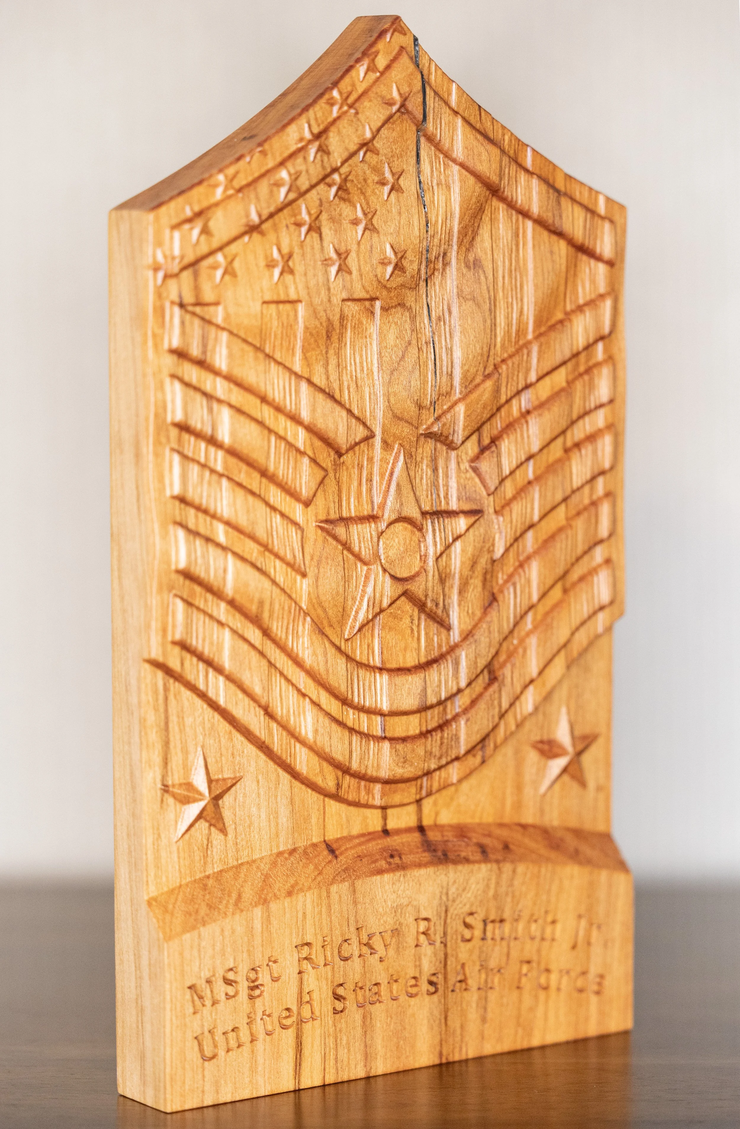 Close-up of a wooden block with an engraved American flag and stars, and engraved text.