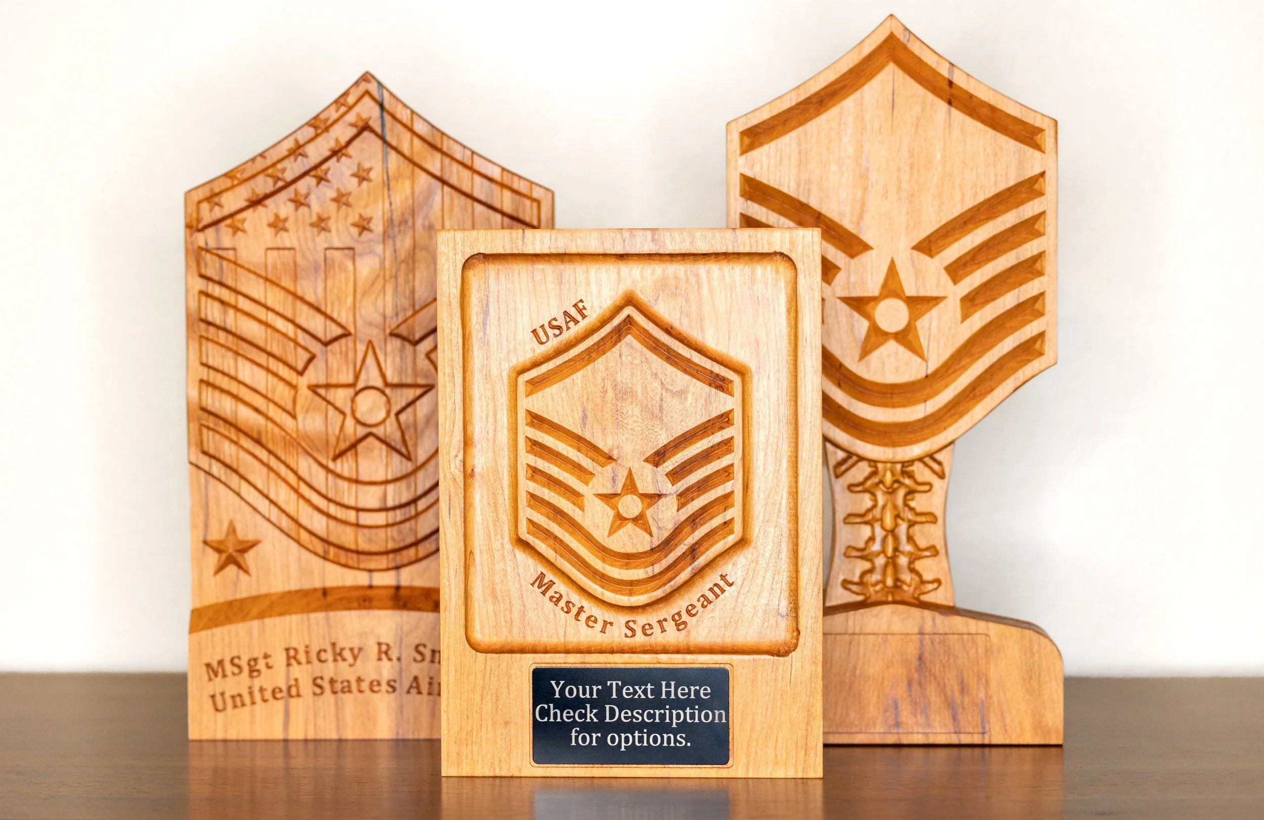 Three wooden plaques with engraved military badges and text, one prominently displaying a shield with stars and stripes design and the words "Master Sergeant" and "Your Text Here."