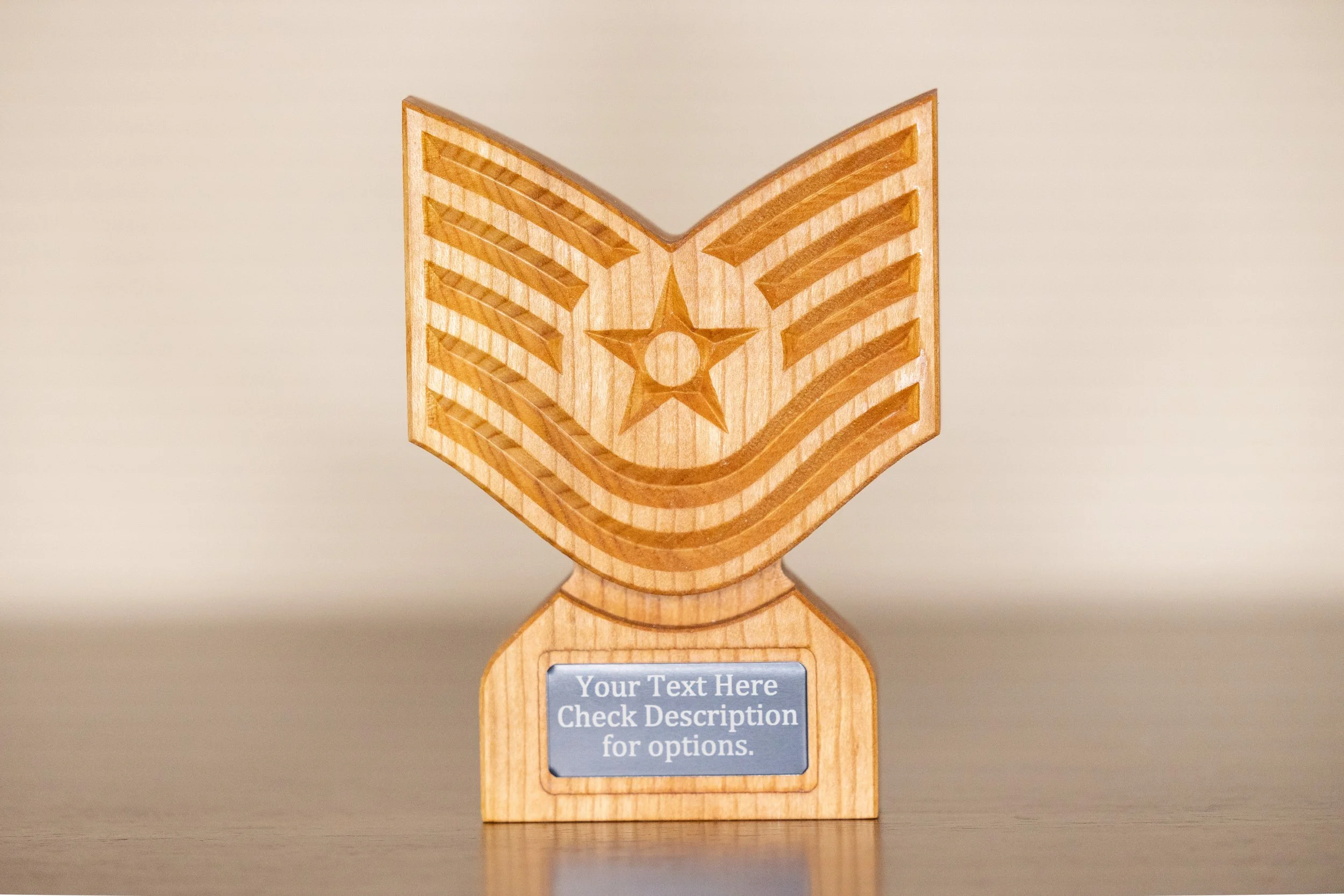 Wooden award trophy with a star and chevron design on its face, and a placeholder for custom text on a gray plaque, set against a plain background.