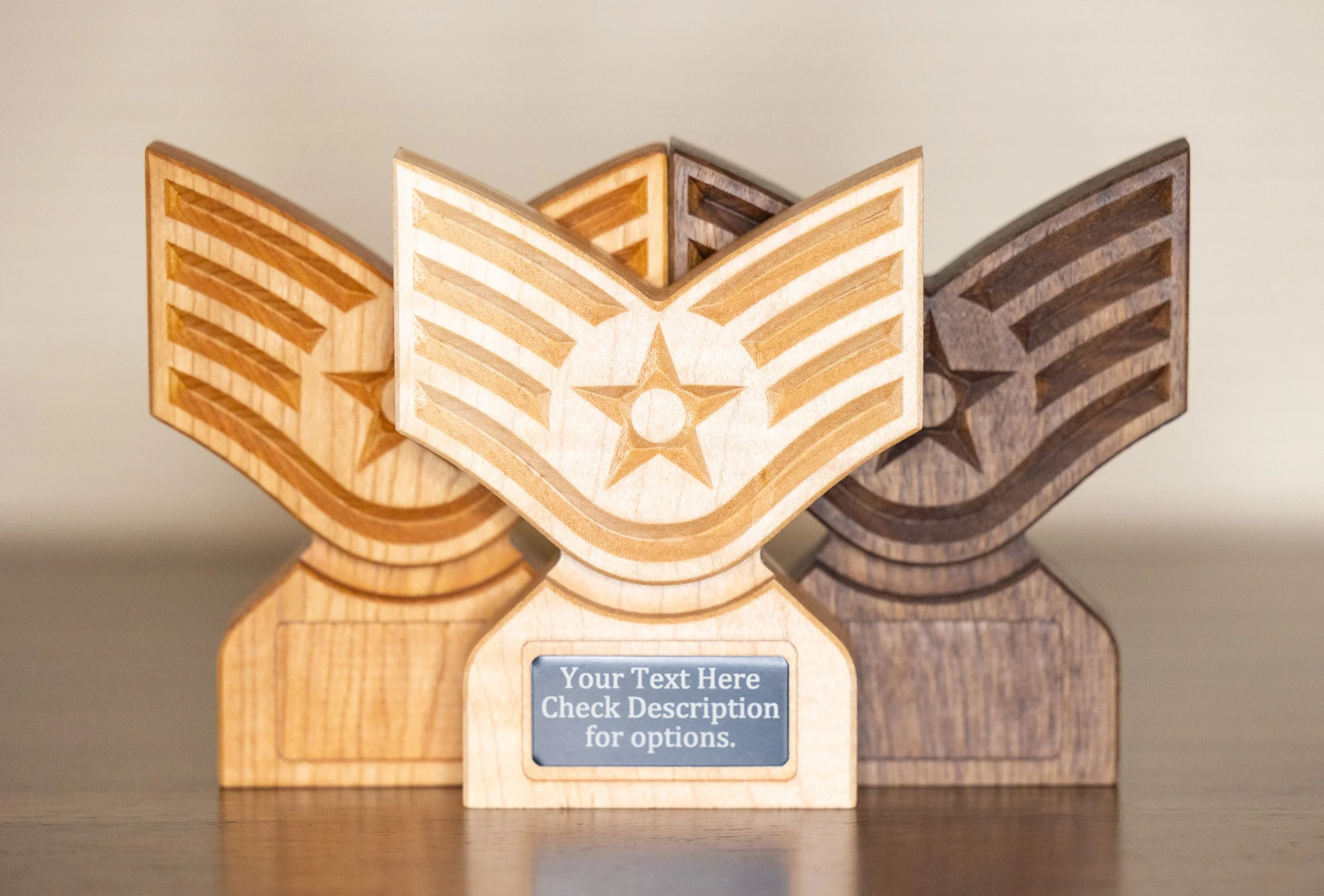 Three wooden trophies with engraved designs and a placeholder for custom text, displayed on a dark surface.