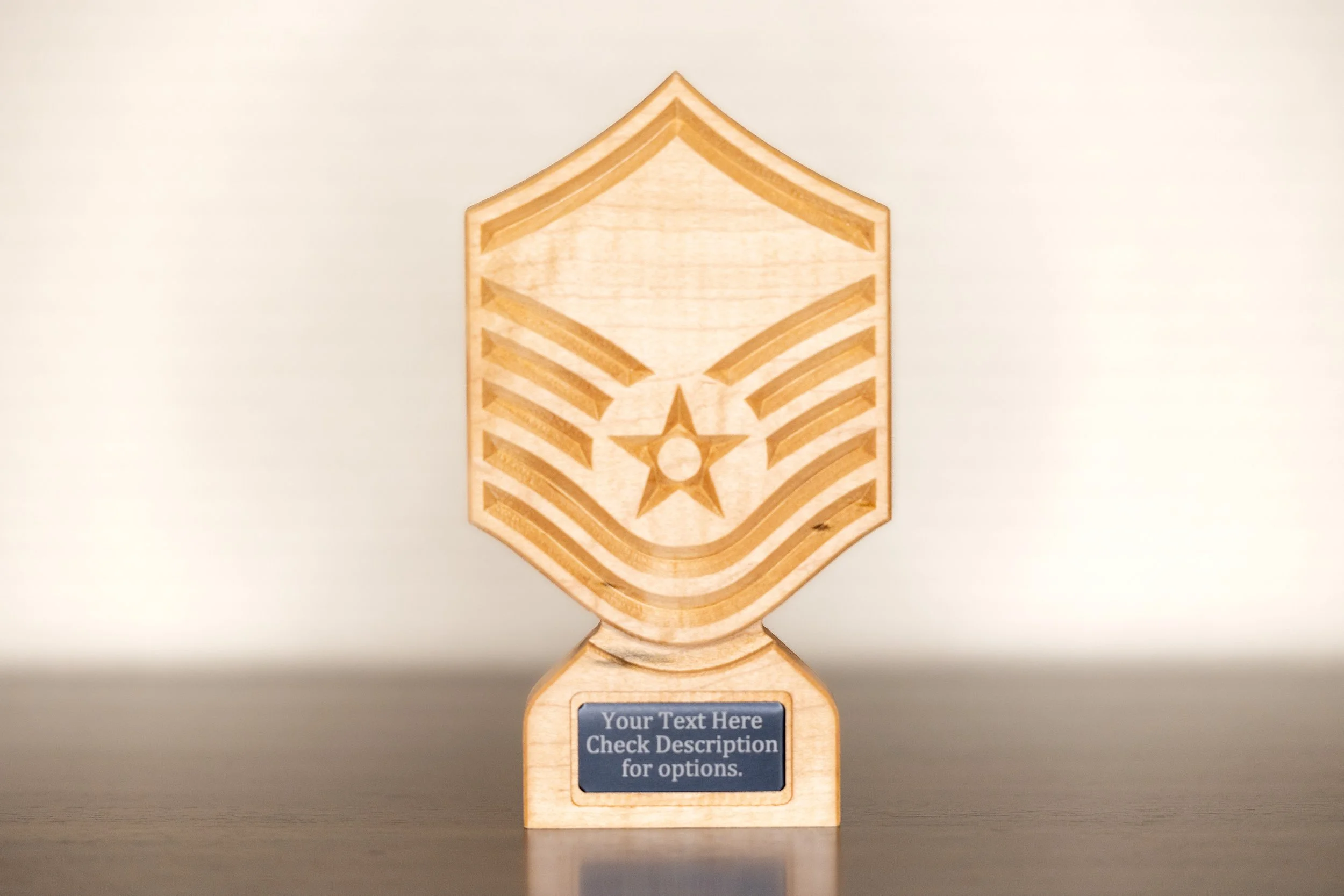 A wooden trophy with a star and stripes engraved on it, mounted on a stand with a customizable plaque area that currently reads 'Your Text Here Check Description for options.'