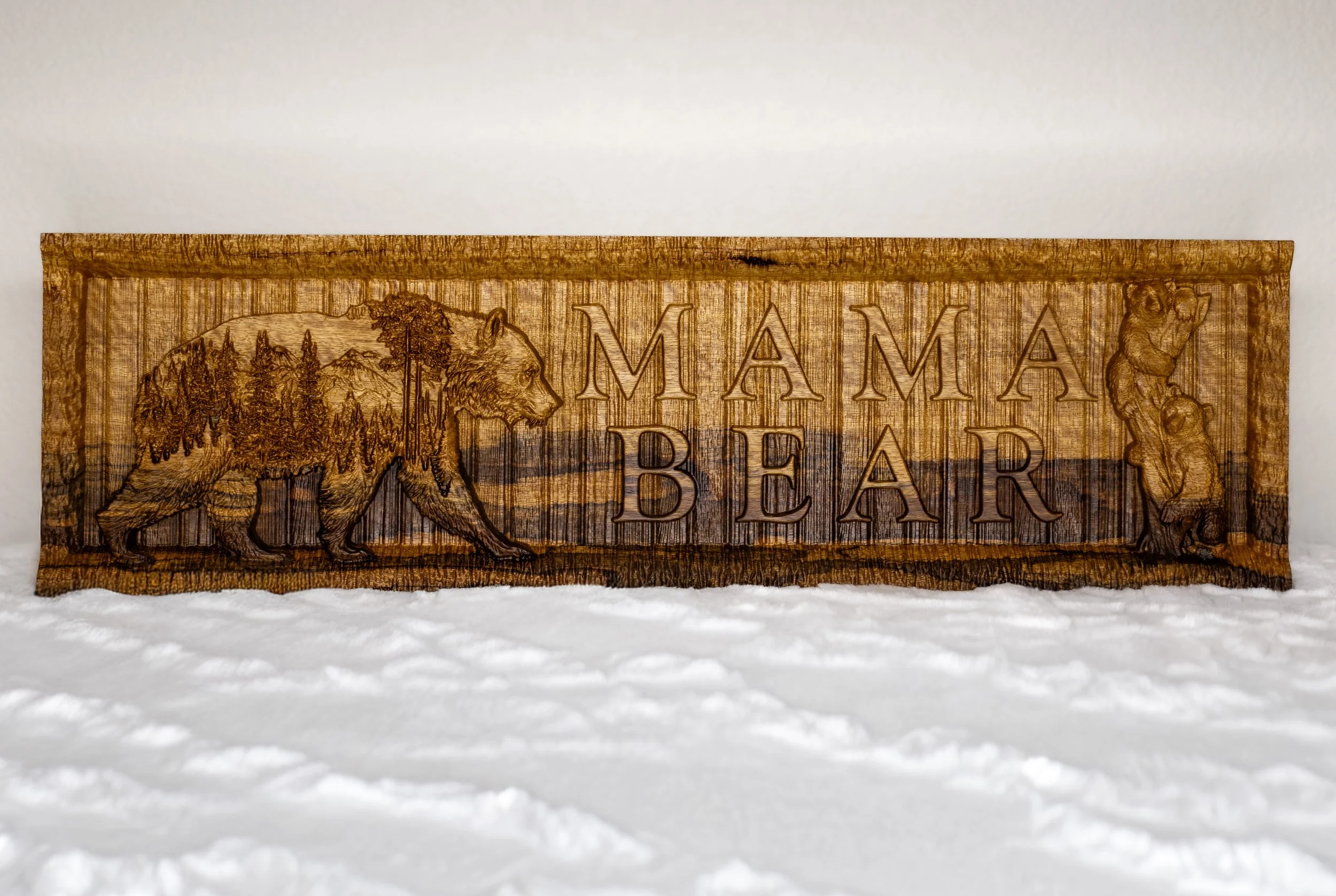 Wooden sign with engraved images of a bear and a mountain landscape, and the words 'Mama Bear'.