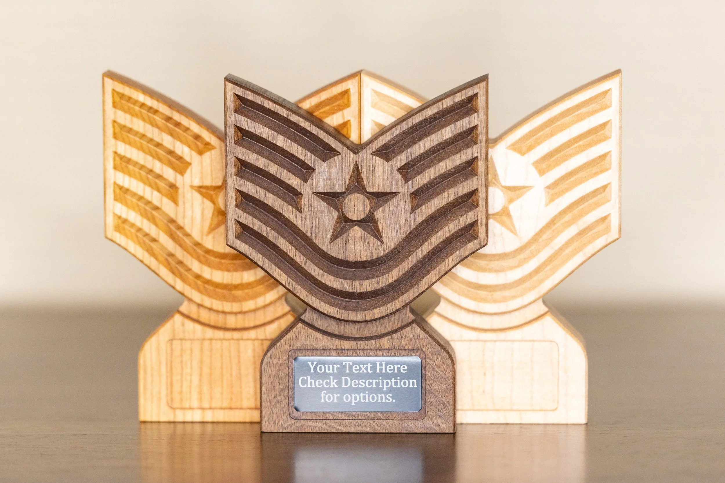 Three wooden medals with star shapes and striped patterns, one central dark wood and two lighter woods, positioned on a flat surface.