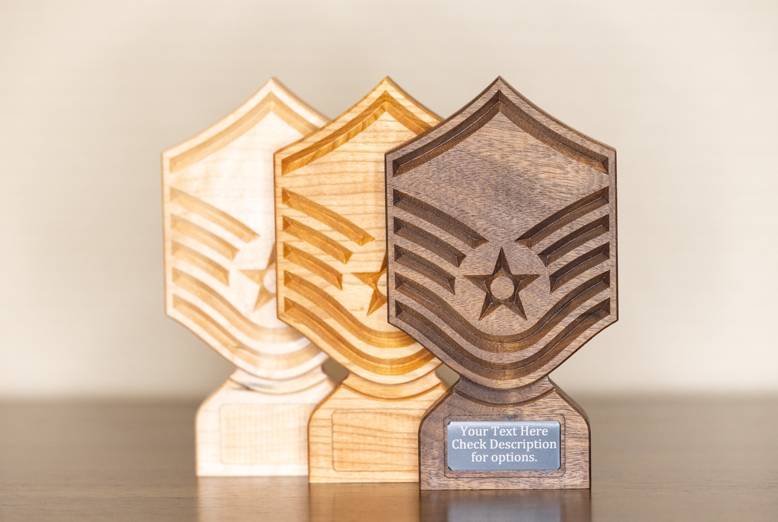 Three wooden military-style plaques in different wood tones display engraved chevrons and a star, with a placeholder text on the front plaque for customization.