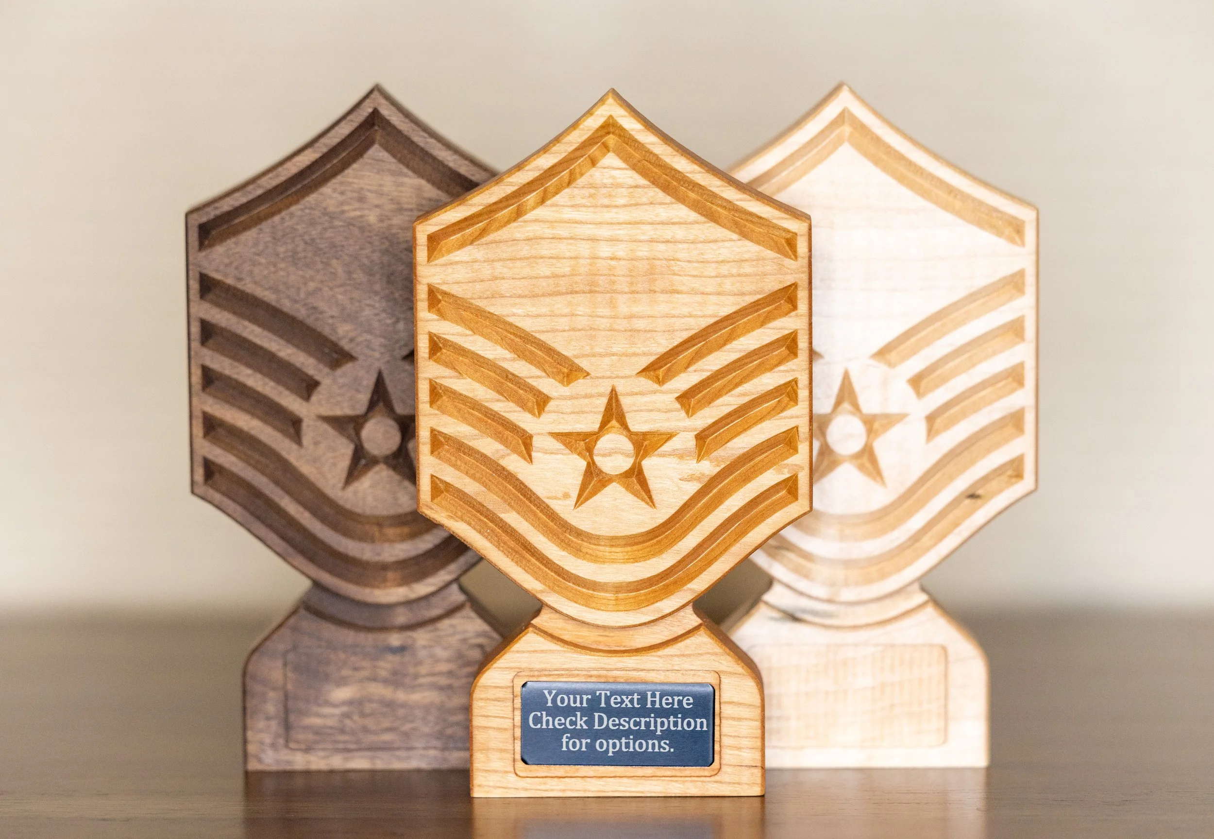 Three wooden trophies with raised star designs and a space for text on the base, standing on a wooden surface against a plain background.