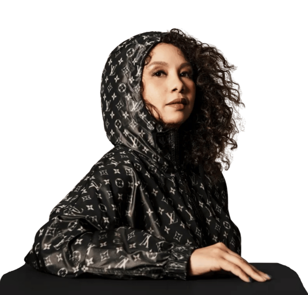 Woman with curly hair wearing a black Louis Vuitton patterned hooded jacket