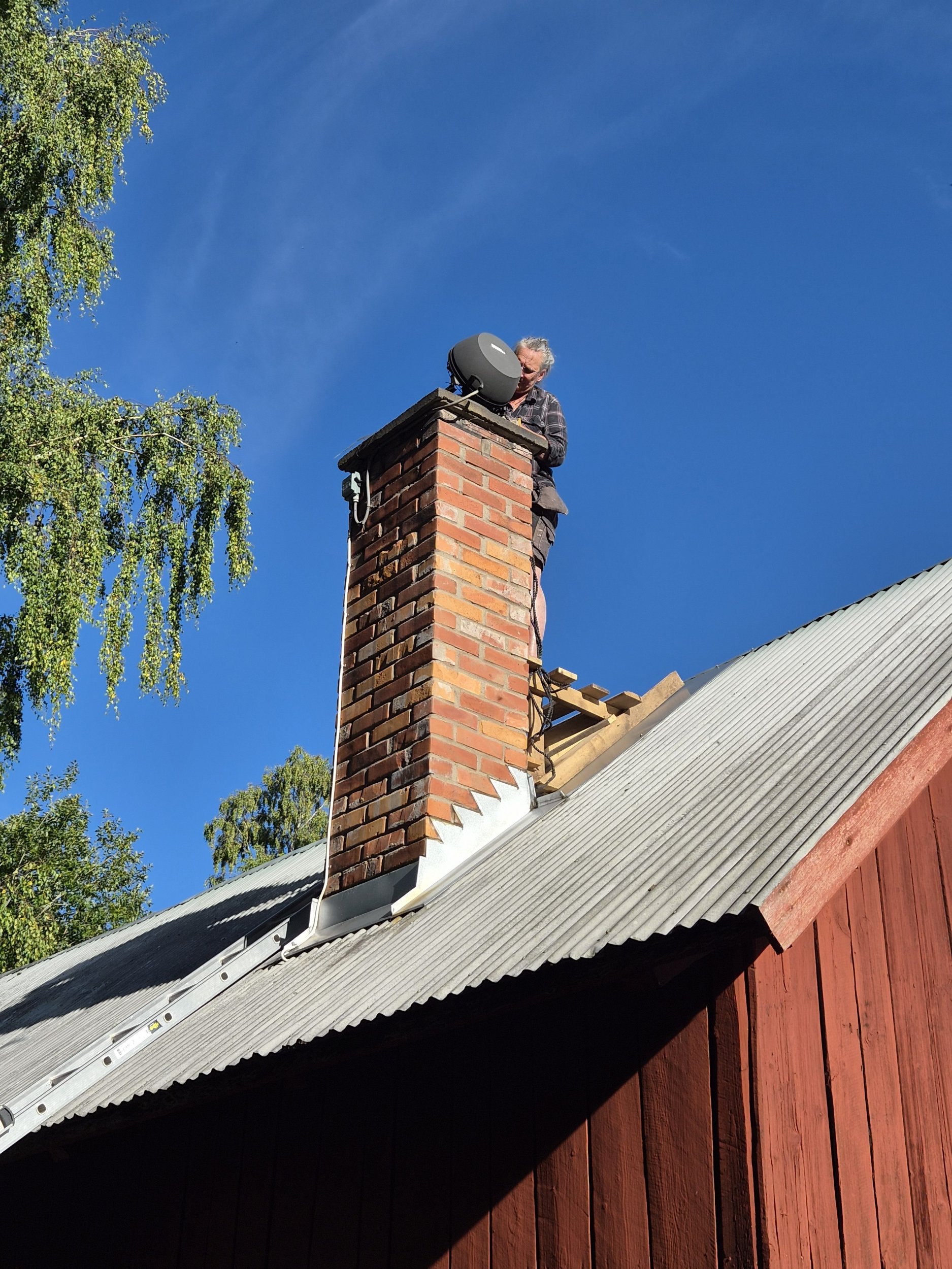 Person vi smedjans skorsten, sotar och sätter gnistskydd runt fläkten