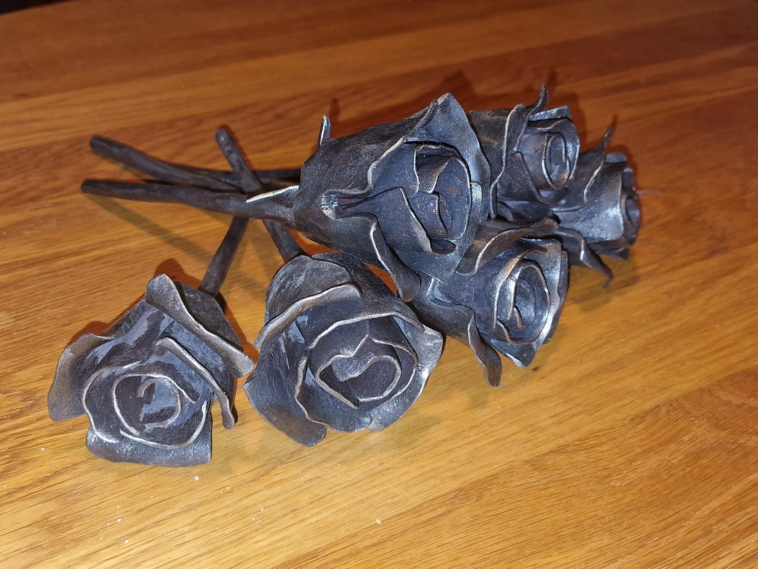 En metallskulptur av en ros på ett träbord.