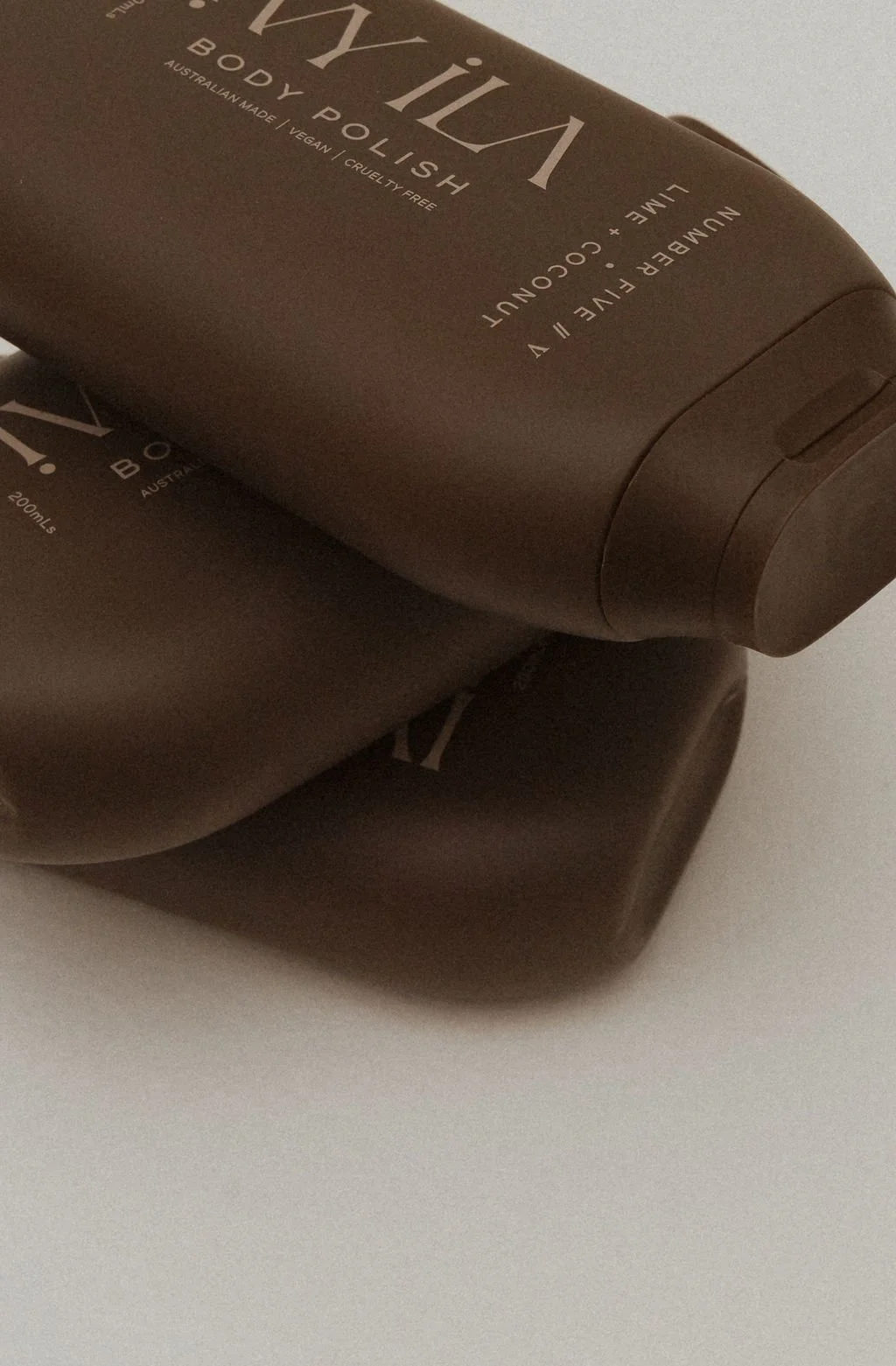 Two brown bottles of Body Polish with white text on the labels, placed on a white surface.