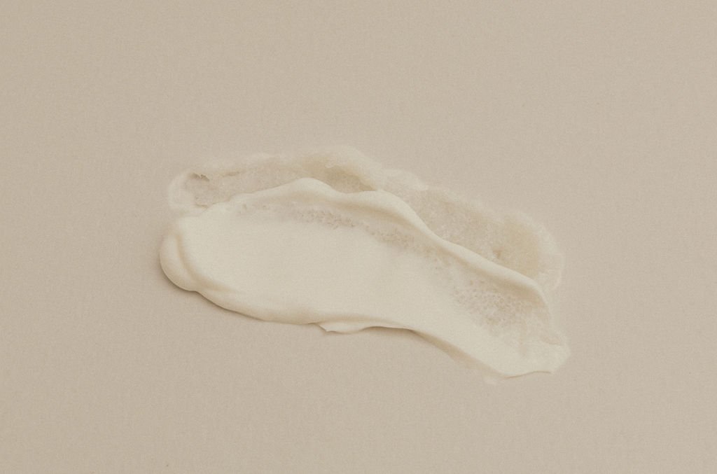 A smear of white paint or cream on a plain, light-colored surface.