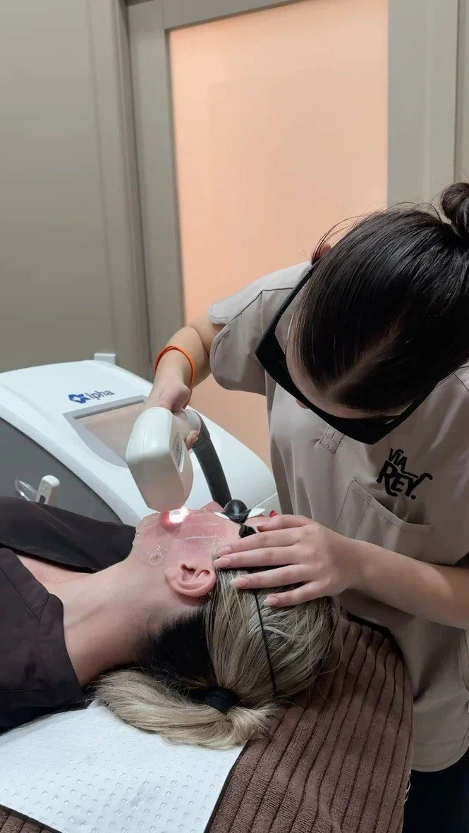 A person receiving a facial treatment with ultrasound device at a spa or skincare clinic.