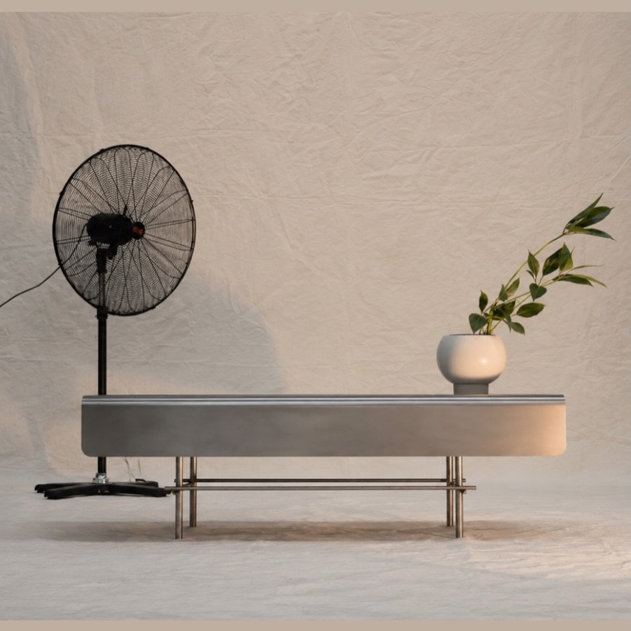 A table, a plant, and a fan doing their best.
