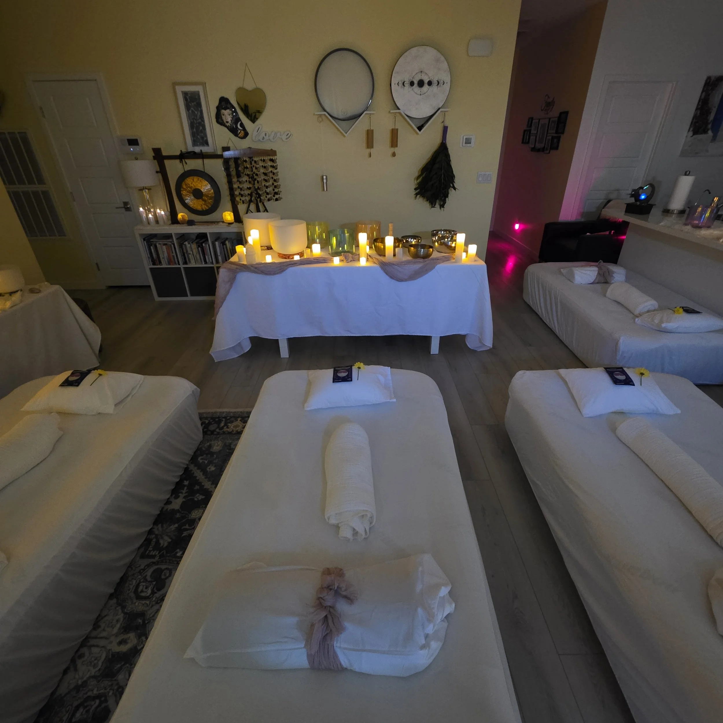 Elevated immersive sound bath space prepared with crystal singing bowls, candlelight, and cushioned beds designed to support relaxation, nervous system restoration, and intentional rest.