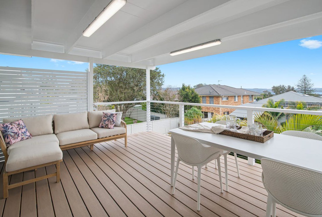 Stunning Outdoor patio with composite deck built by Platinum Decks with a scenic neighbourhood view with trees and houses under a blue sky.
