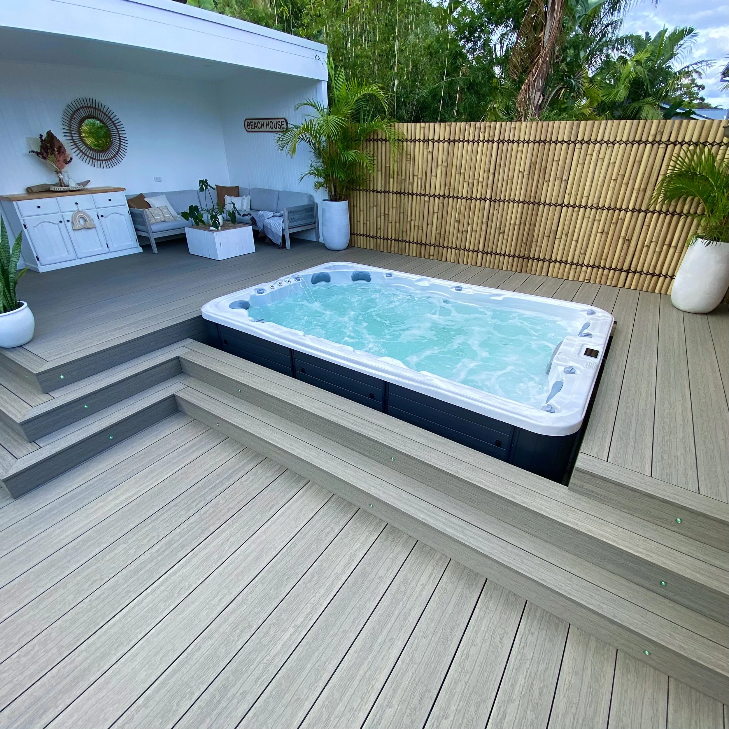 A light grey composite deck built around a modern spa with bamboo screening and soft planting, designed by Platinum Decks for coastal outdoor living