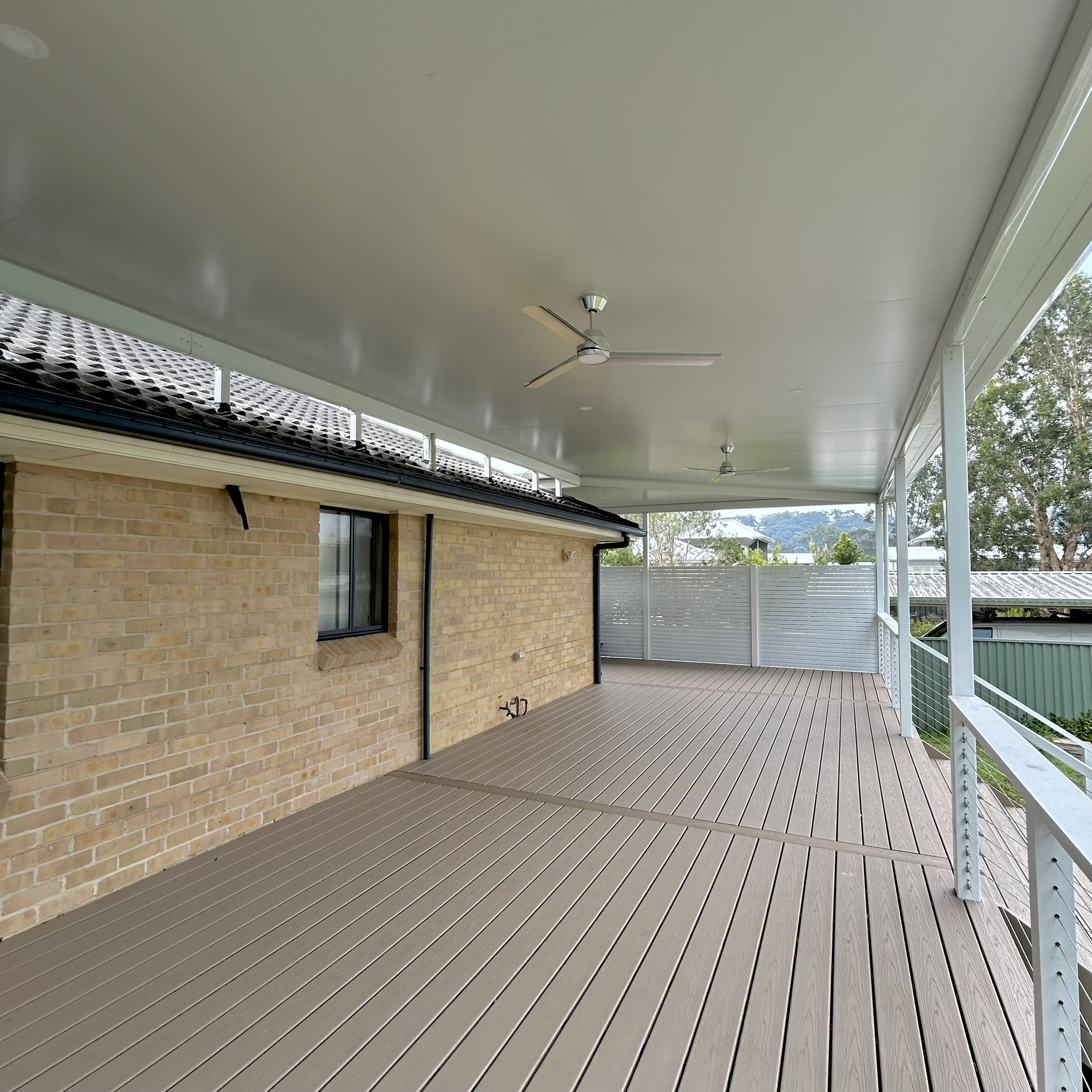 Composite deck under a covered outdoor patio roof installed and completed with care by the Platinum Decks crew