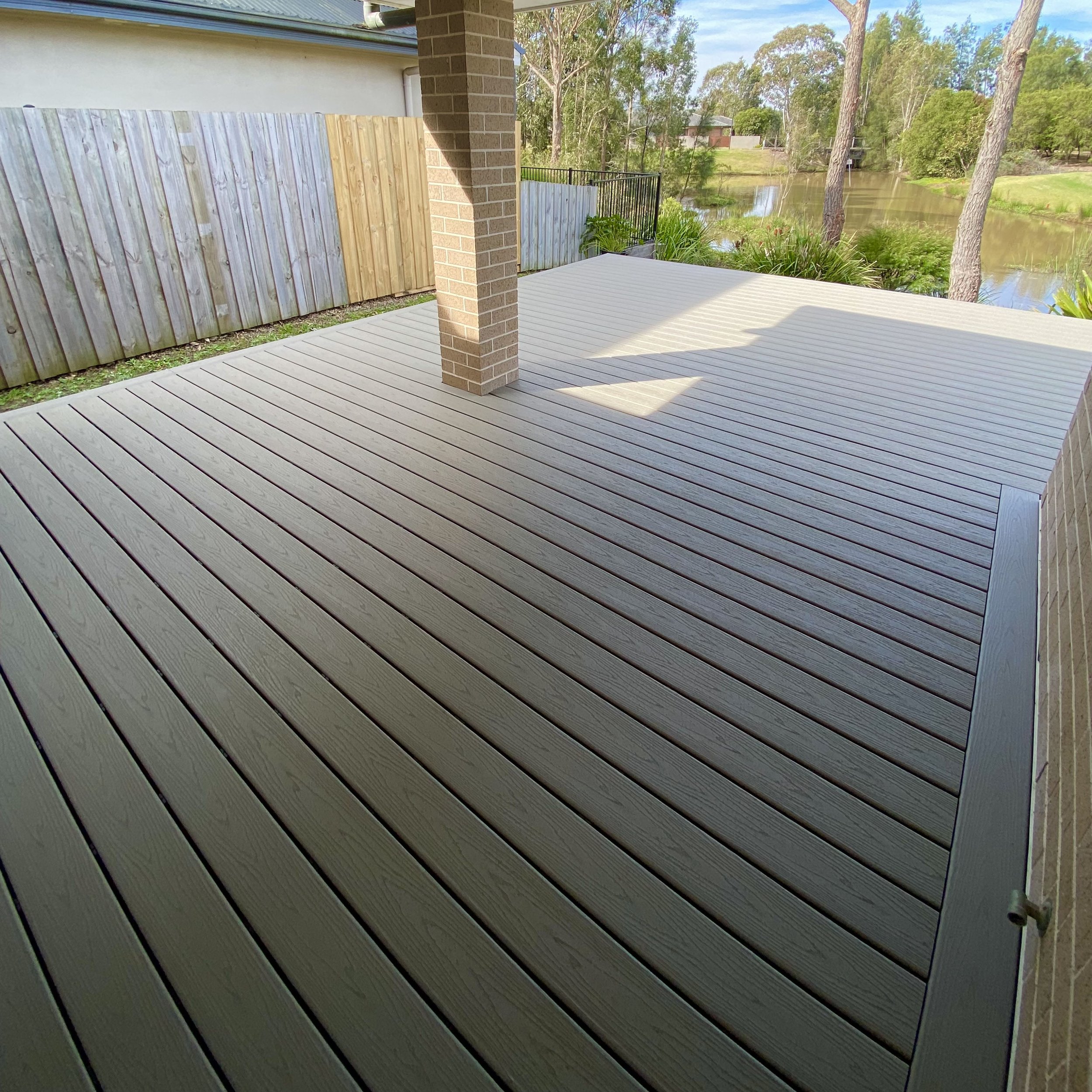 Composite Trex deck overlooking landscaped pond and garden designed by Platinum Decks to deliver a refined, high‑end backyard experience