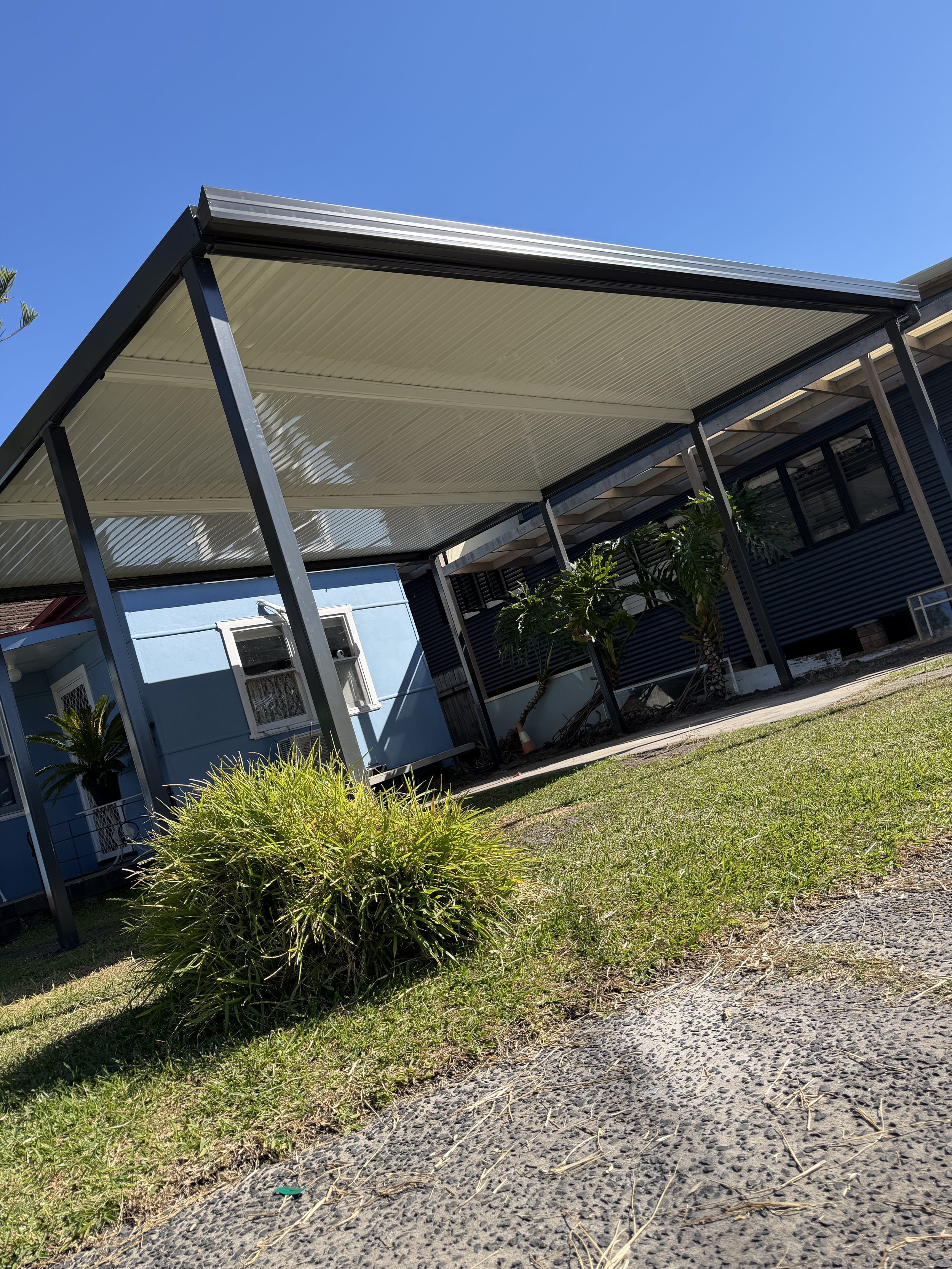 Stratco outback carport, garden plants and open lawn completed by Platinum Decks to provide a sleek, functional outdoor entertaining space