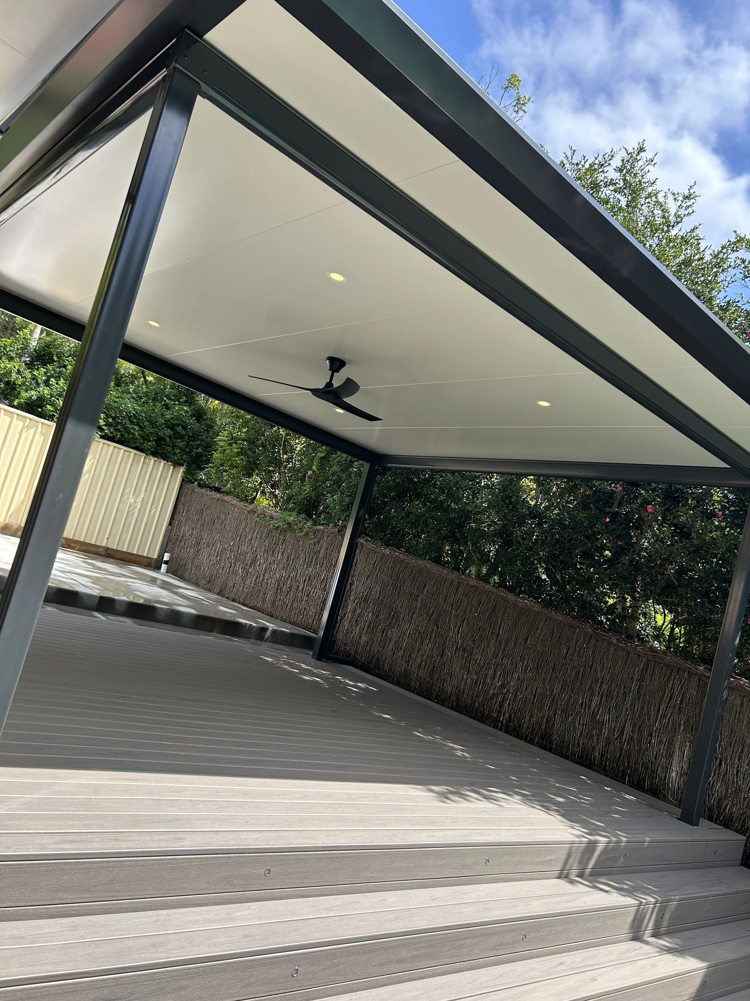 Stratco Outback Cooldek patio with ceiling fan, Trex decking and privacy fencing crafted by Platinum Decks to create a premium, sheltered alfresco zone
