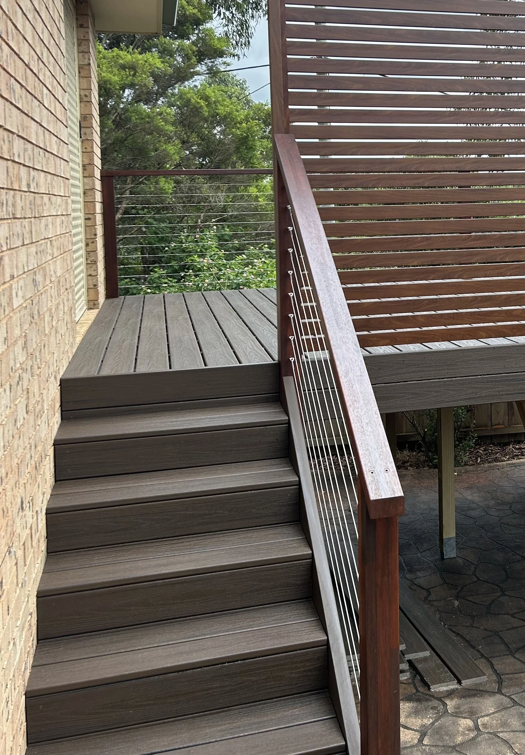 Brown composite stair run with a custom handrail crafted by Platinum Decks to offer a warm, high‑end feel while standing up to coastal humidity