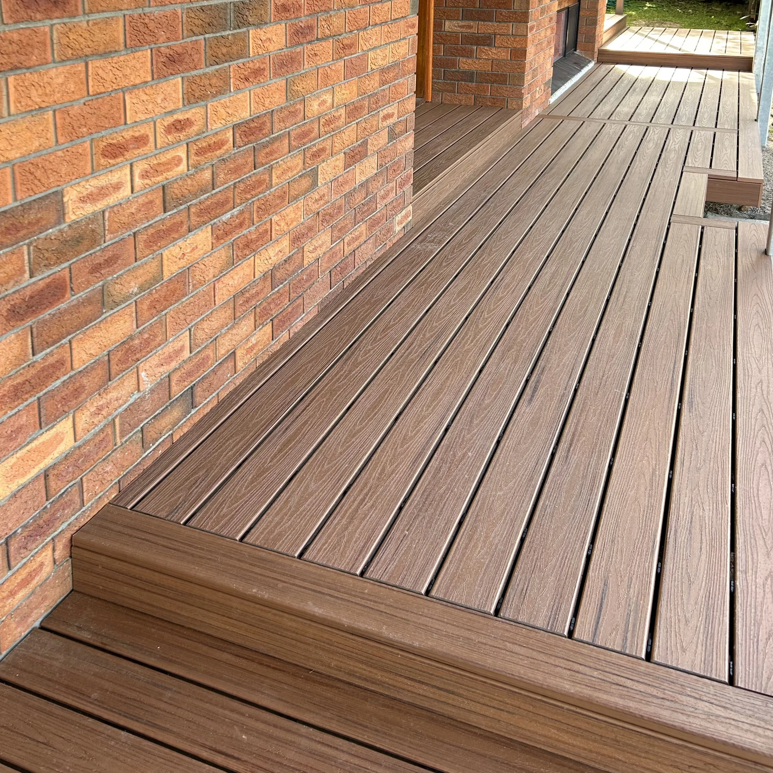 Trex deck with steps leading to sunlit lawn crafted by Platinum Decks to deliver a refined, functional transition between deck and yard