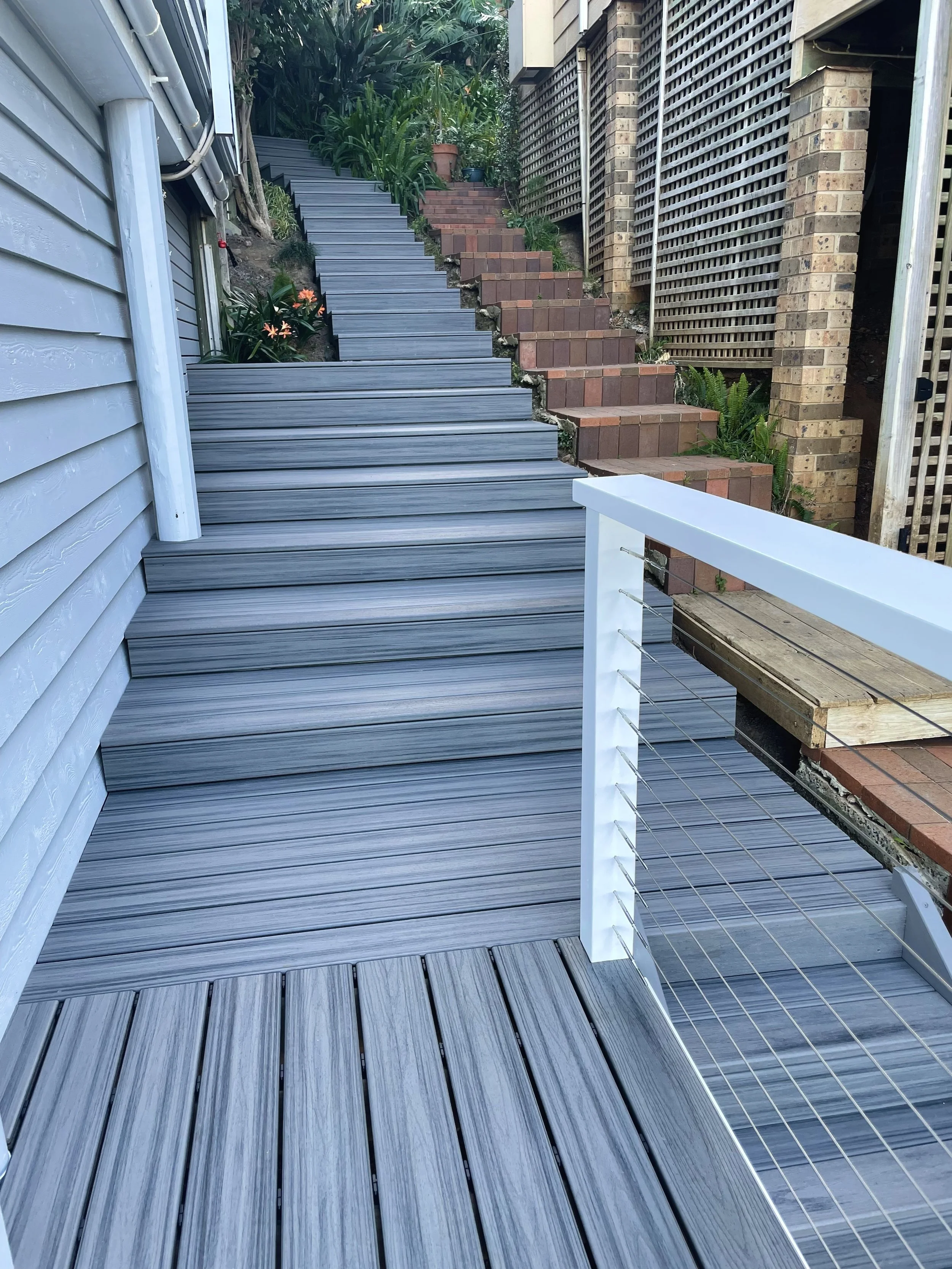Composite staircase leading to an elevated entry built with coastal‑grade materials and finished by Platinum Decks for a clean, modern look that handles salty air with ease
