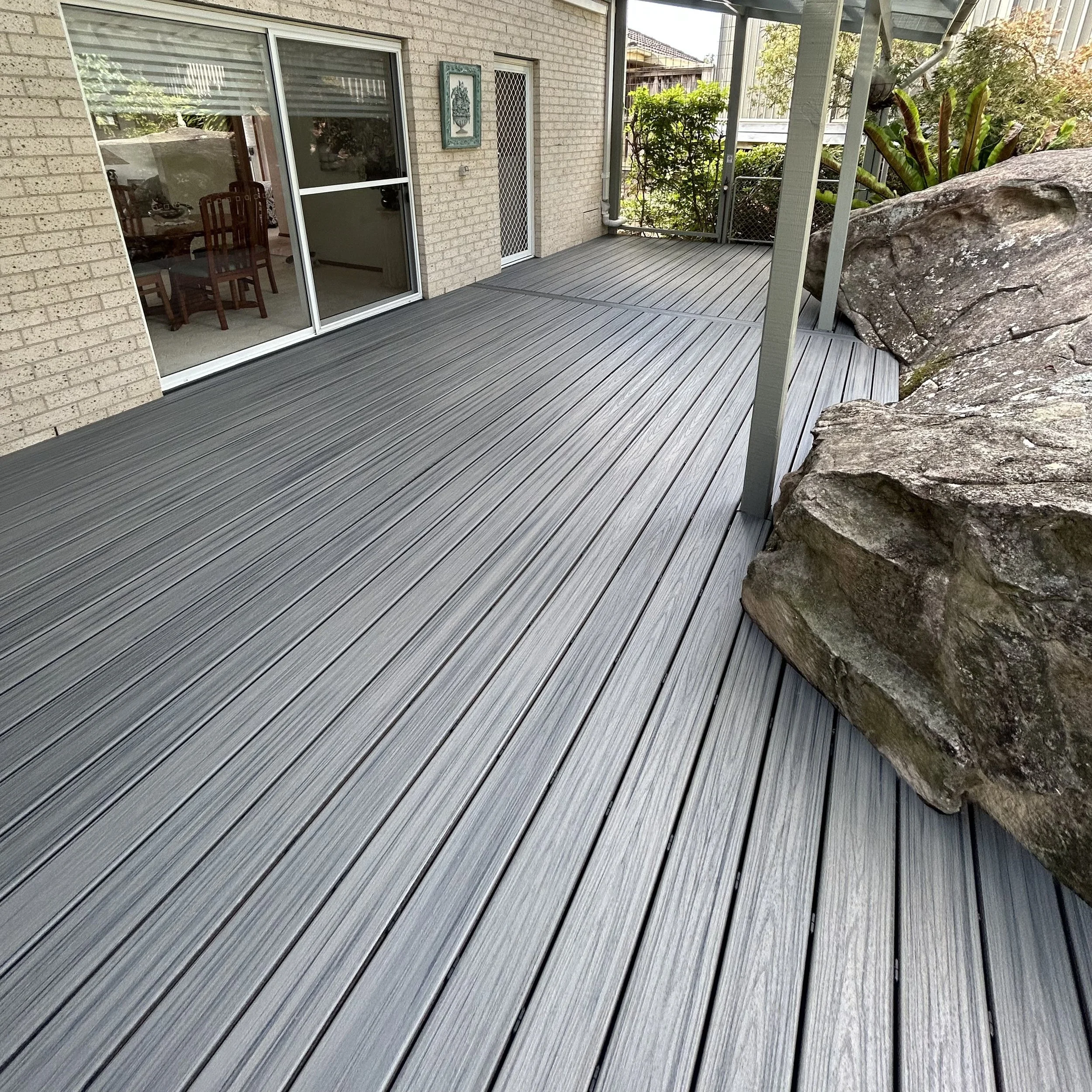A modern composite deck area with built around rocks and garden on the Central Coast by Platinum Decks.