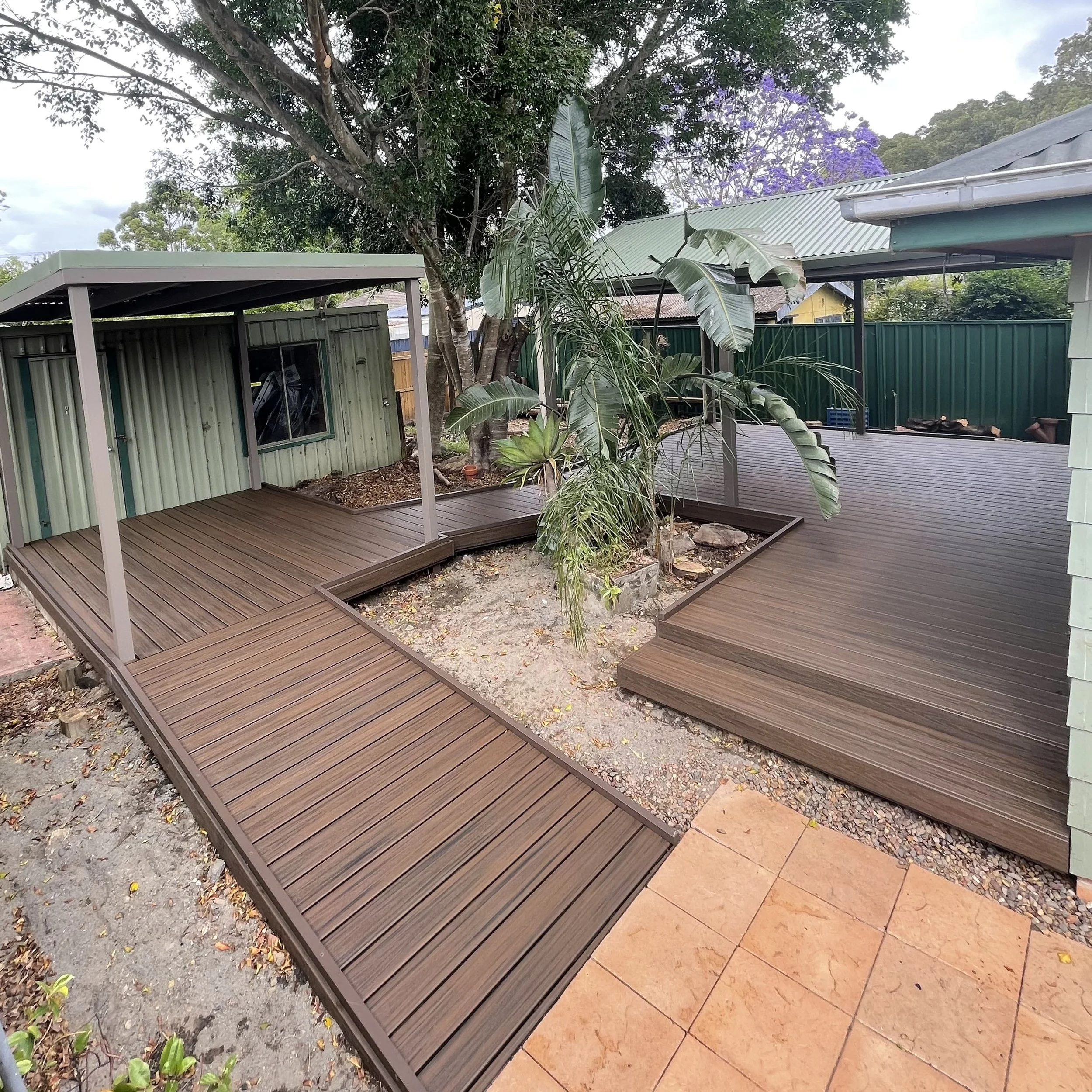 Outdoor landscaped designed backyard with modern composite deck around trees and plants